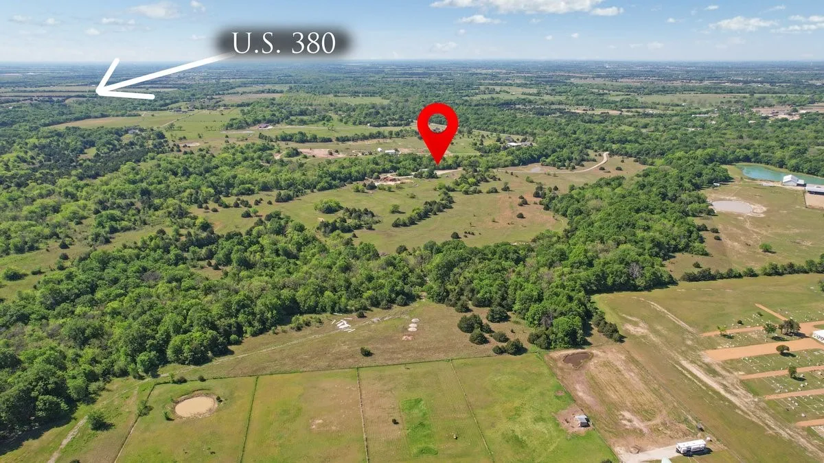 An aerial view of the property, showcasing expansive green fields and mature trees