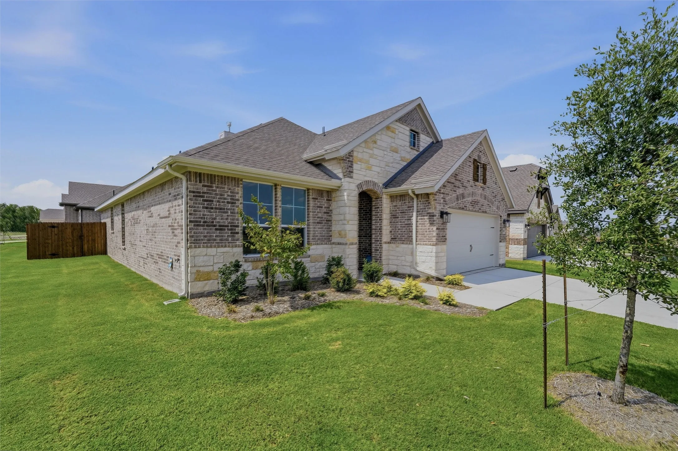 Brick and stone veneer exterior with a gabled roofline, front-facing garage, and concrete driveway