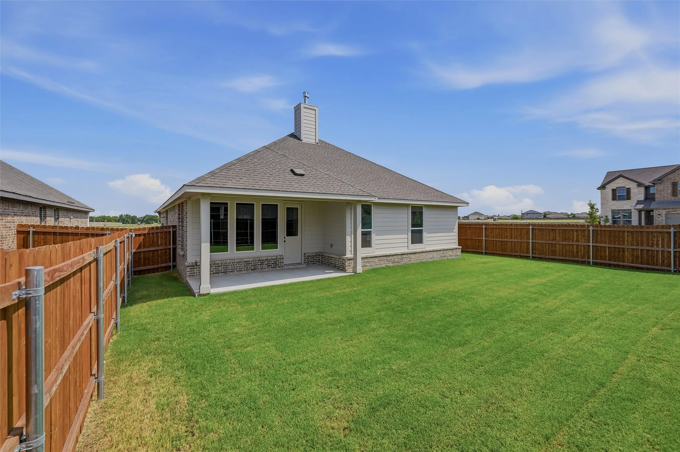 Expansive backyard featuring a manicured lawn, full wood fencing, and a concrete patio