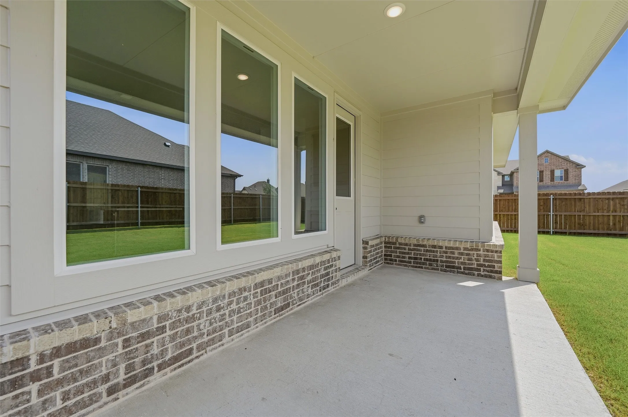 Covered patio featuring a concrete surface, brick base, and recessed lighting