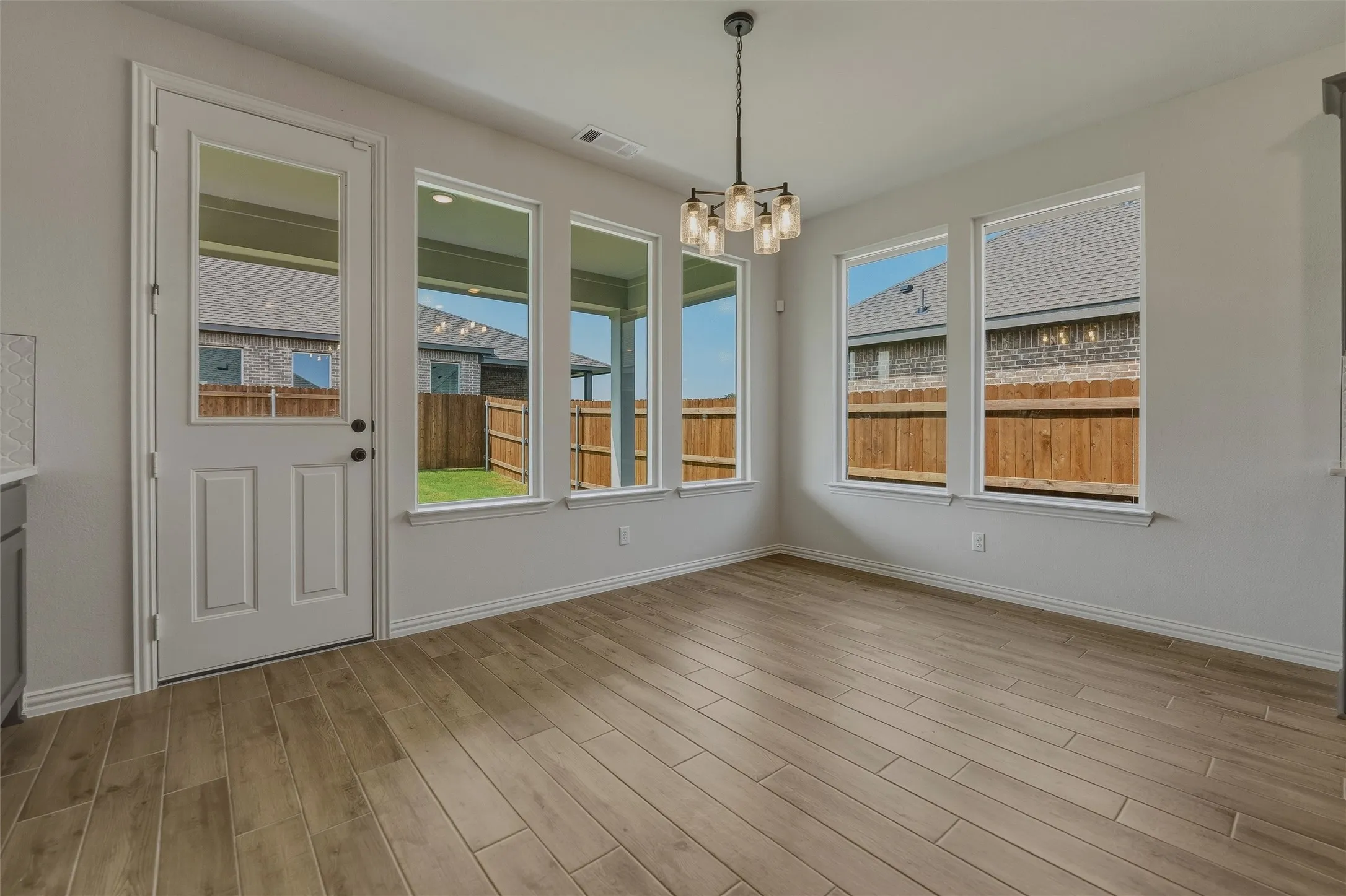 Wood-finish flooring, multiple large windows, and a glass-paneled exterior door