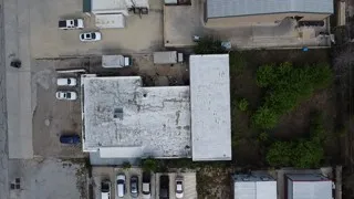 Aerial view of the property showing buildings with white roofs and surrounding paved areas