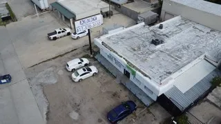 Aerial view of the property, showcasing a flat roof and a paved parking area
