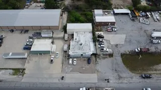 Aerial view of the property showing multiple commercial buildings with flat roofs and ample paved parking areas