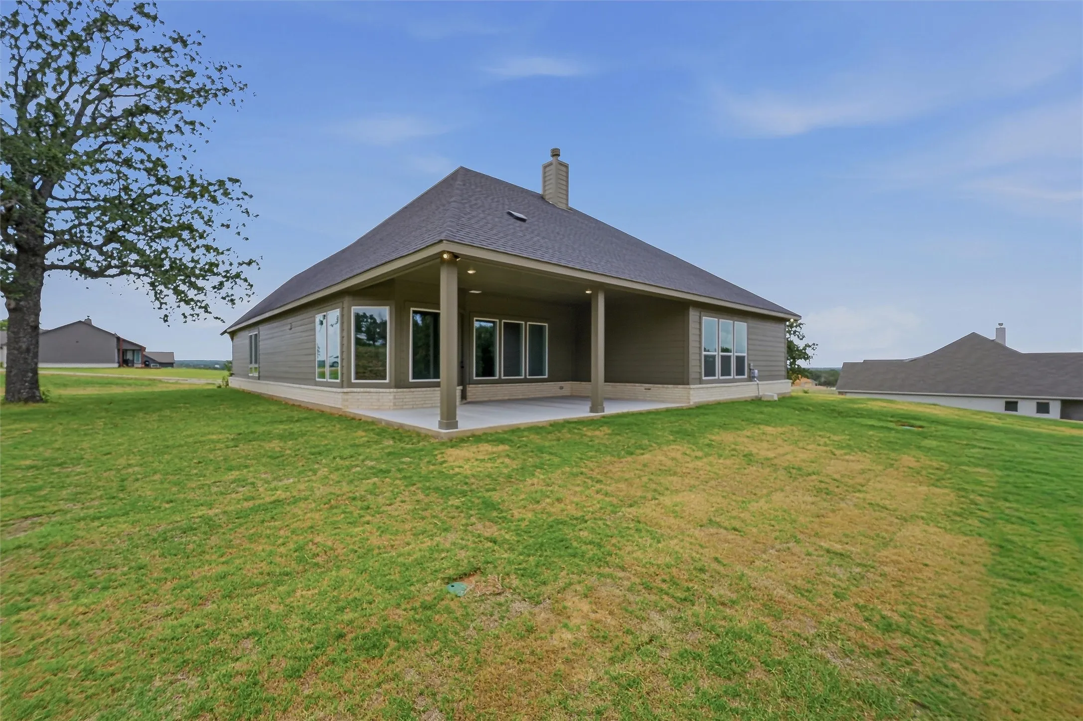 Rear exterior with a covered patio, multiple windows, and a chimney feature