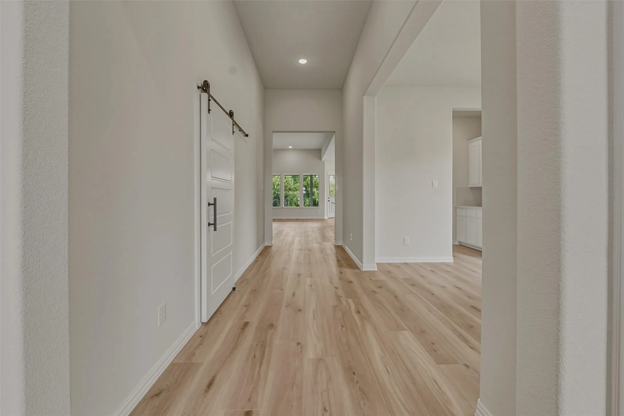Entryway featuring wood-finish flooring, a white barn door with dark hardware, recessed lighting, and a neutral wall palette