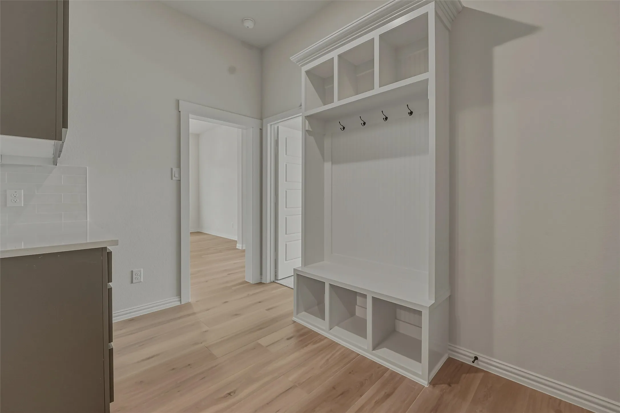 Built-in white storage unit featuring bench seating, upper cubbies, and coat hooks