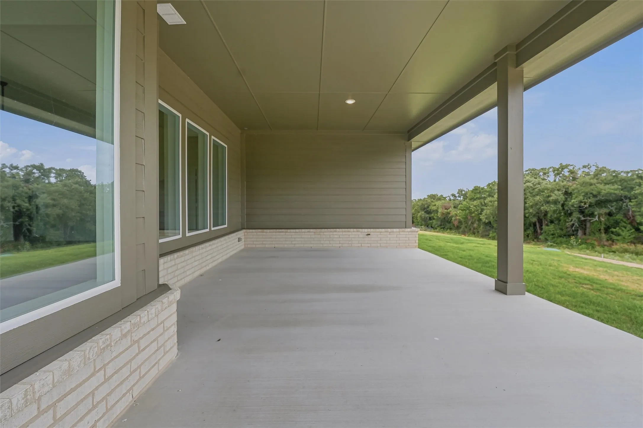 Expansive covered patio featuring a concrete surface, white brick accents, and a recessed ceiling light