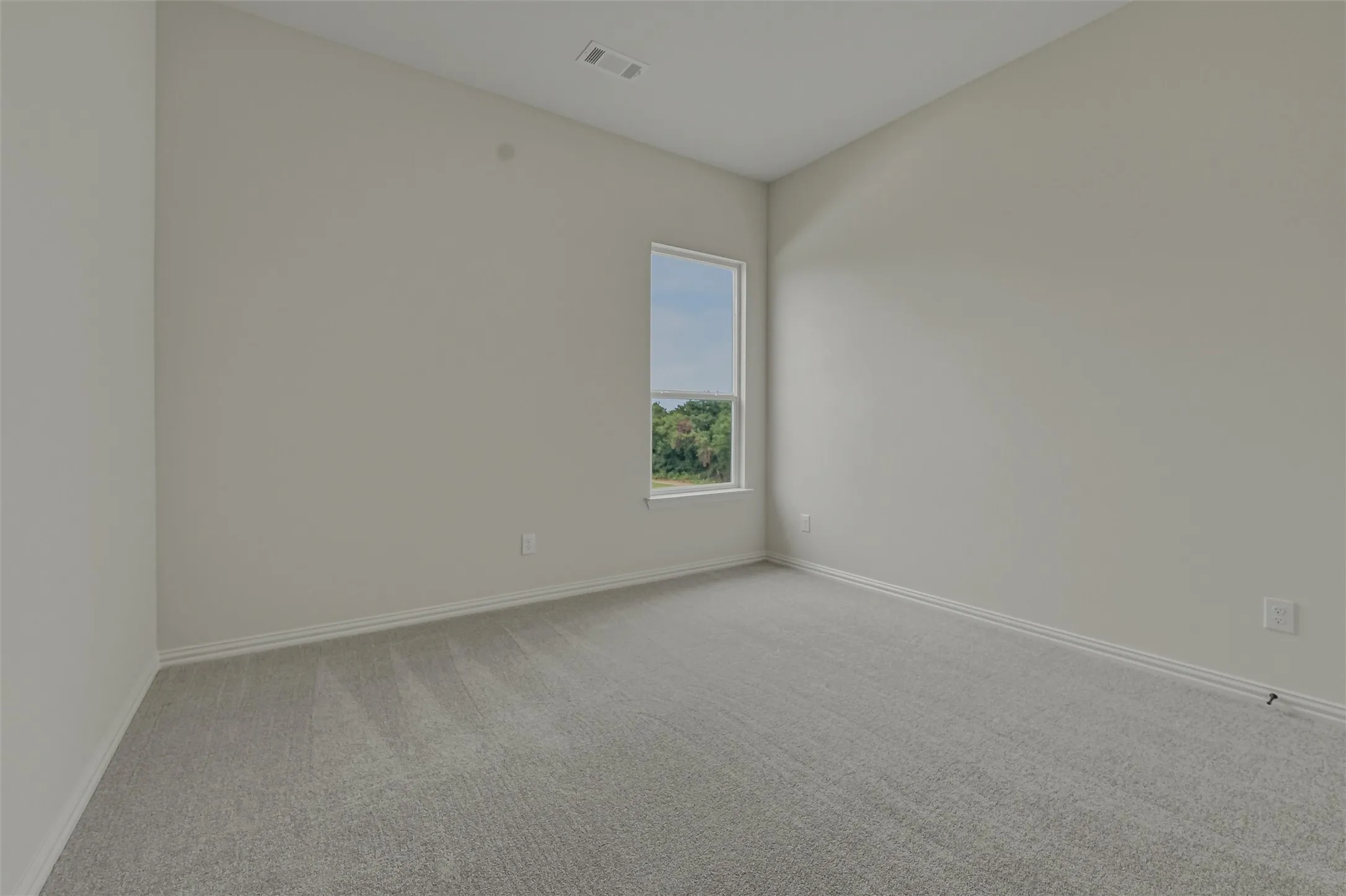 Carpeted room featuring a single window, white baseboards, light grey walls, and a recessed ceiling vent