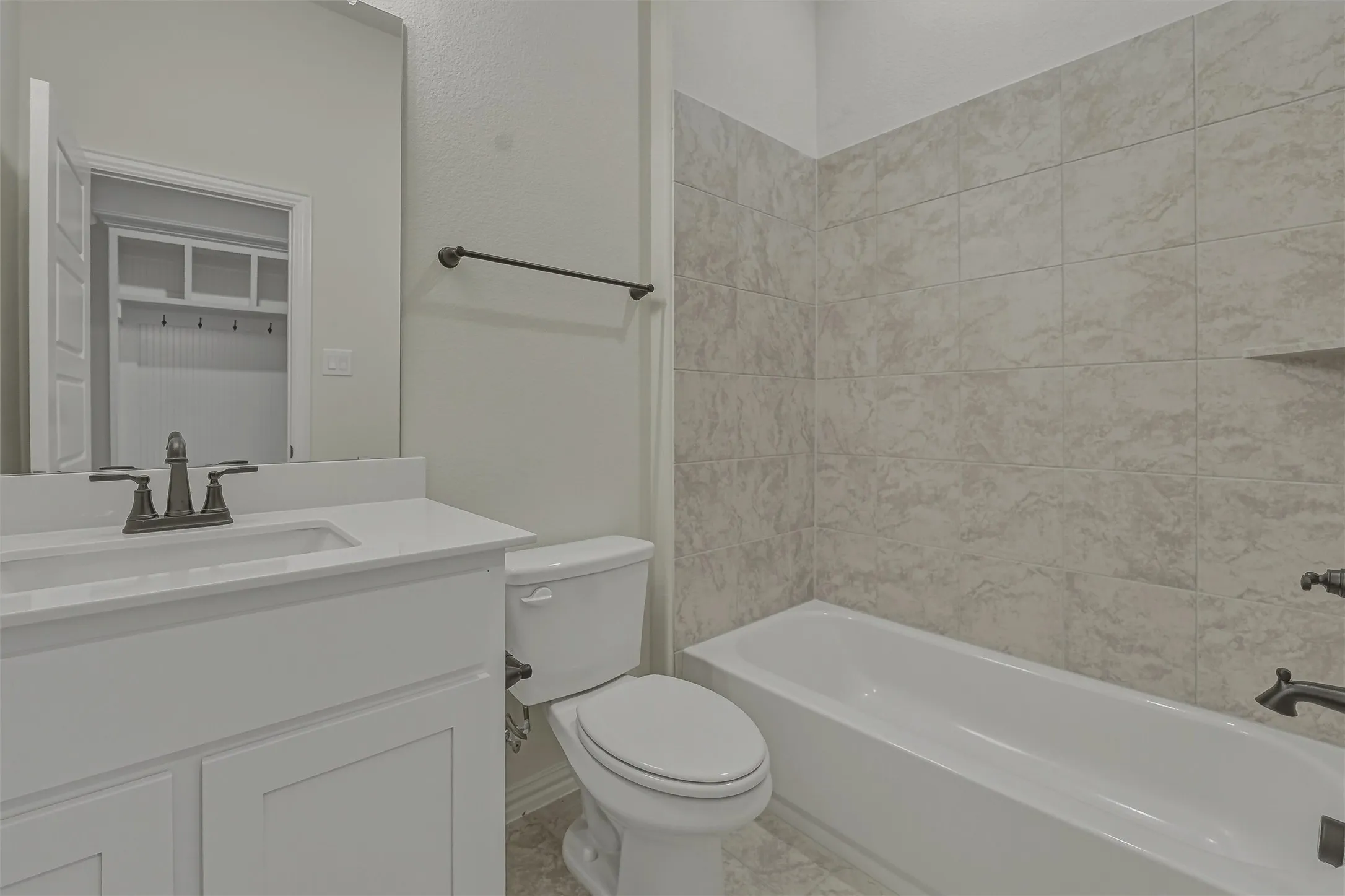 Bathroom featuring a white vanity with an undermount sink, a white countertop, and a dark-finished faucet