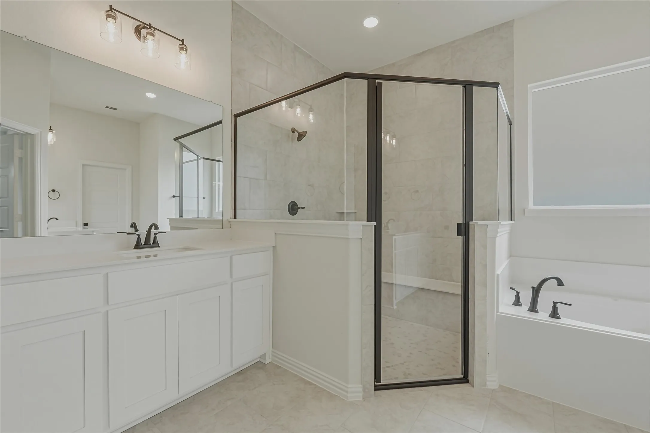 Spacious bathroom featuring a white vanity with integrated sink, black fixtures, a walk-in shower with clear glass enclosure, and a built-in tub