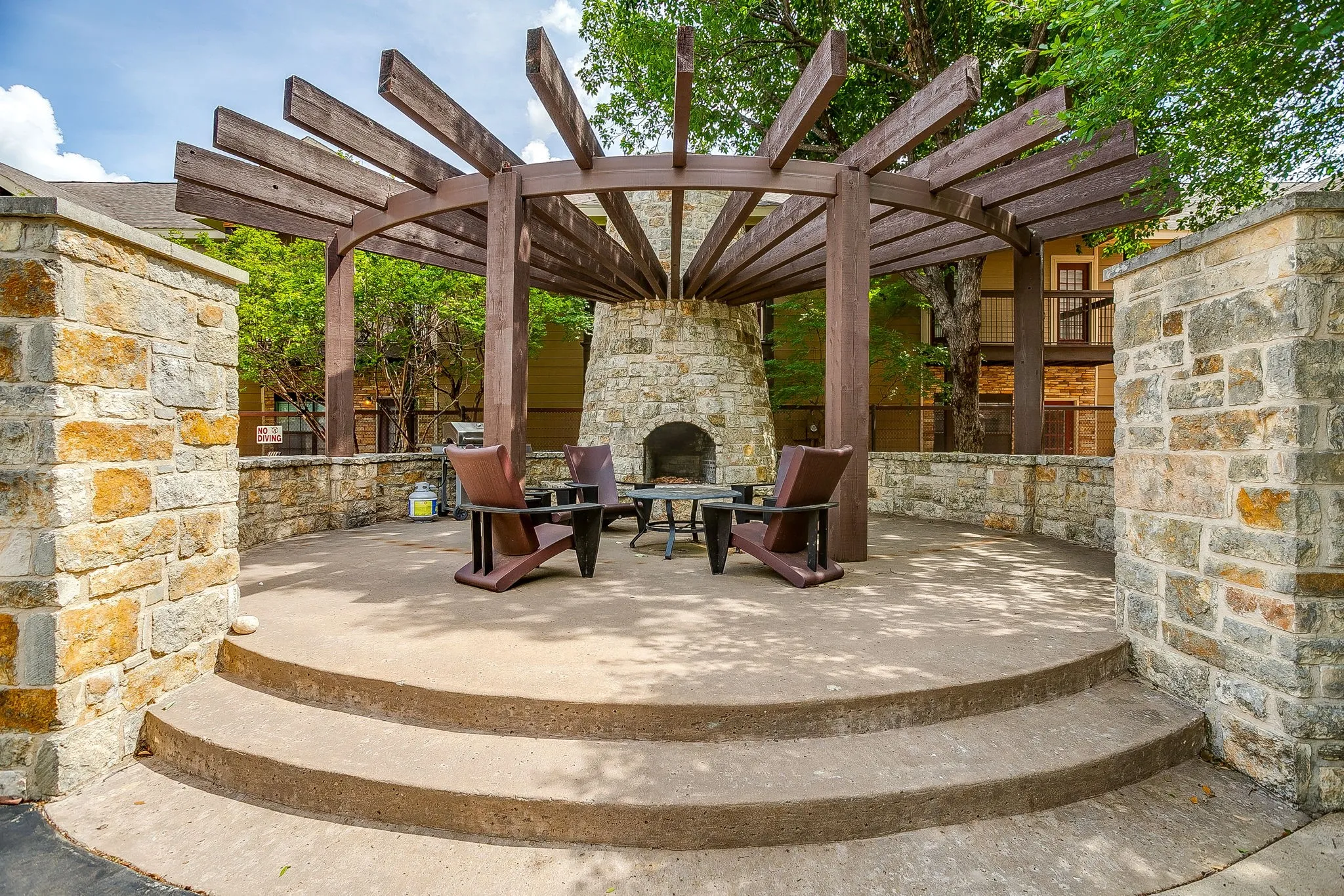 View of patio featuring a pergola and an outdoor stone fireplace