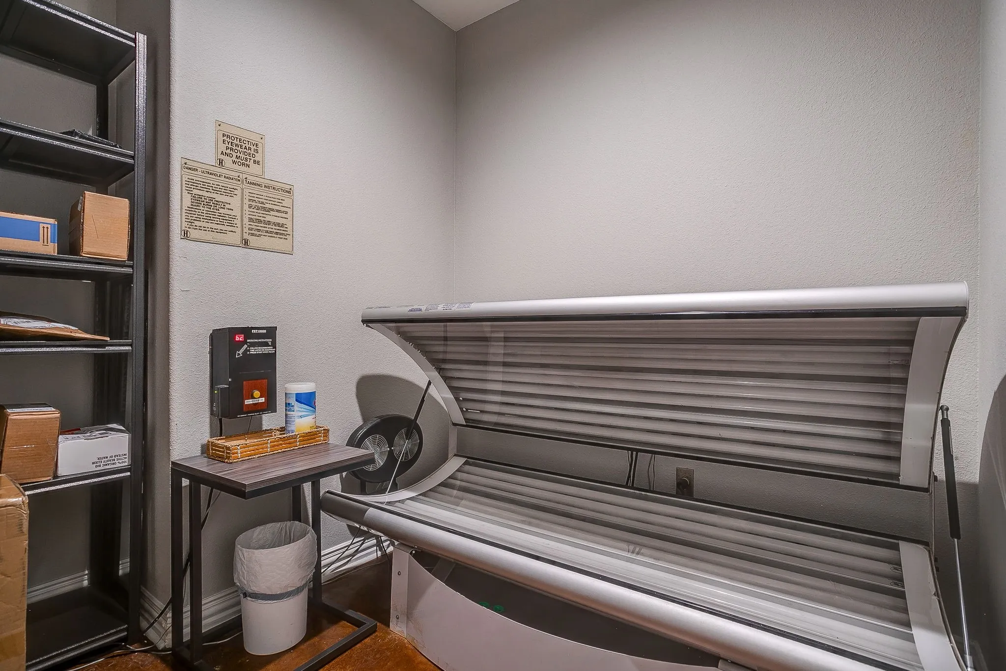 Misc room with a tanning bed and a textured wall