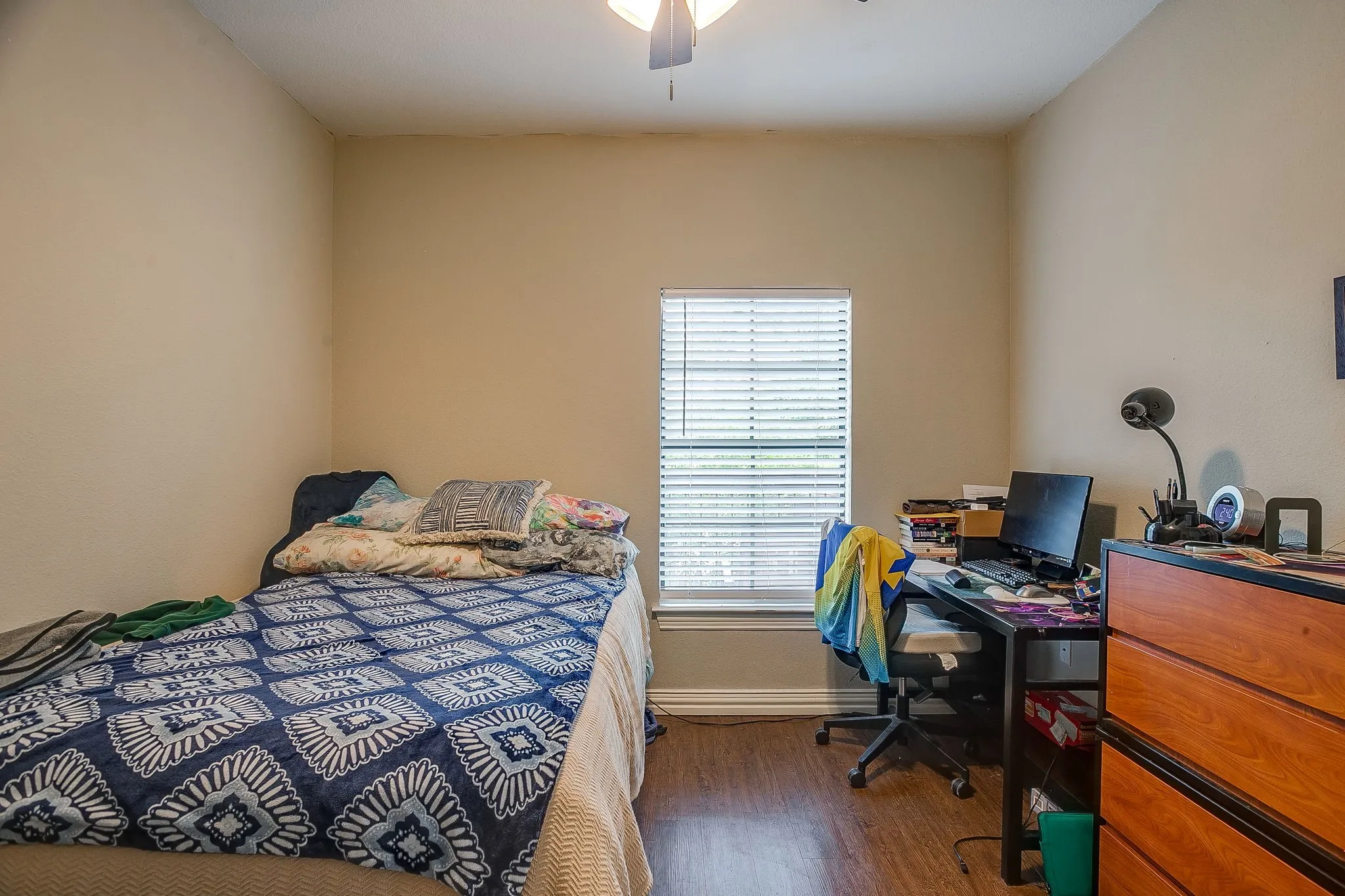 Bedroom with an office area, dark wood-style floors, and ceiling fan