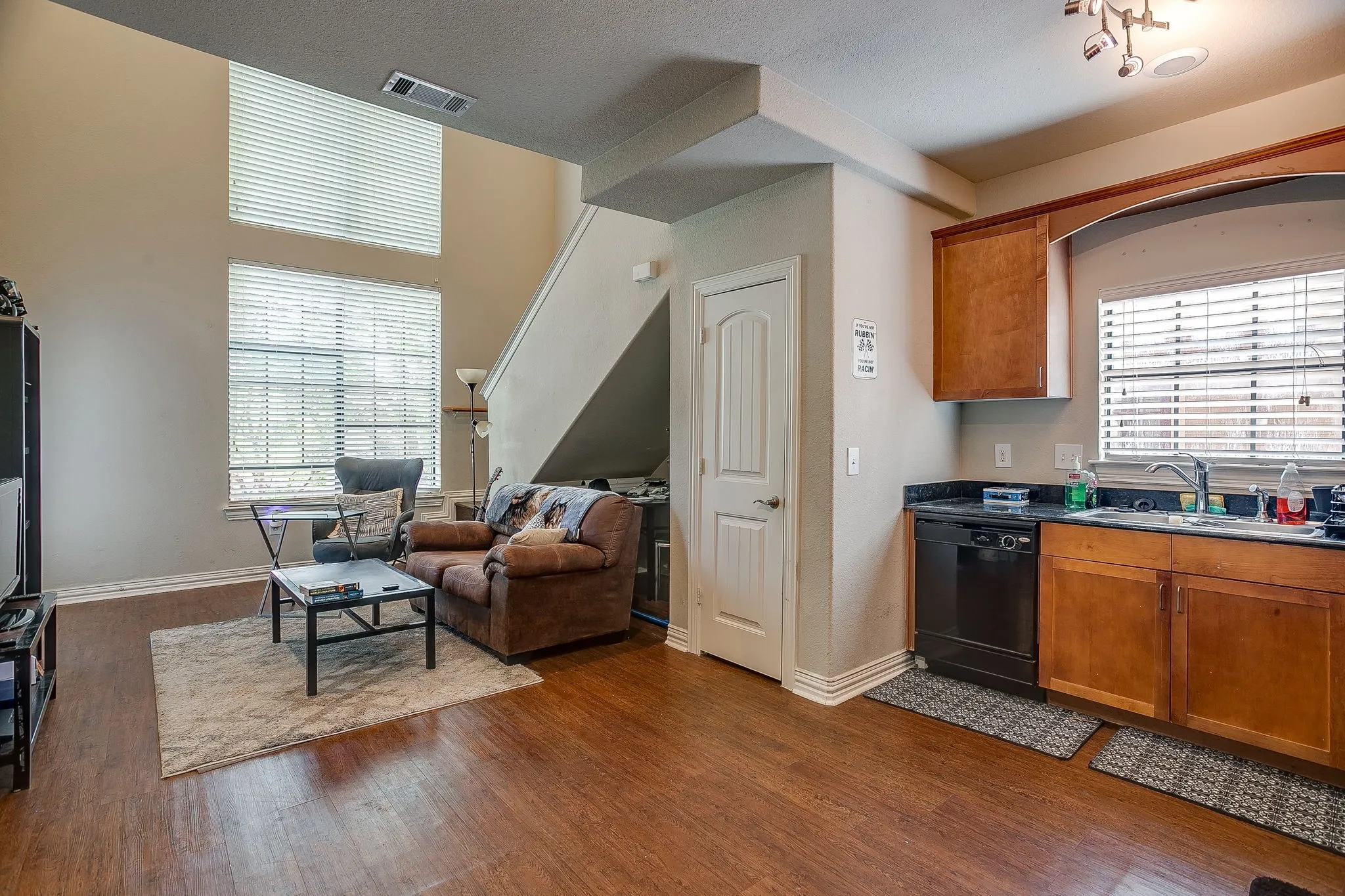 Kitchen with open floor plan, wood finish cabinetry, dishwasher, and dark wood-type flooring