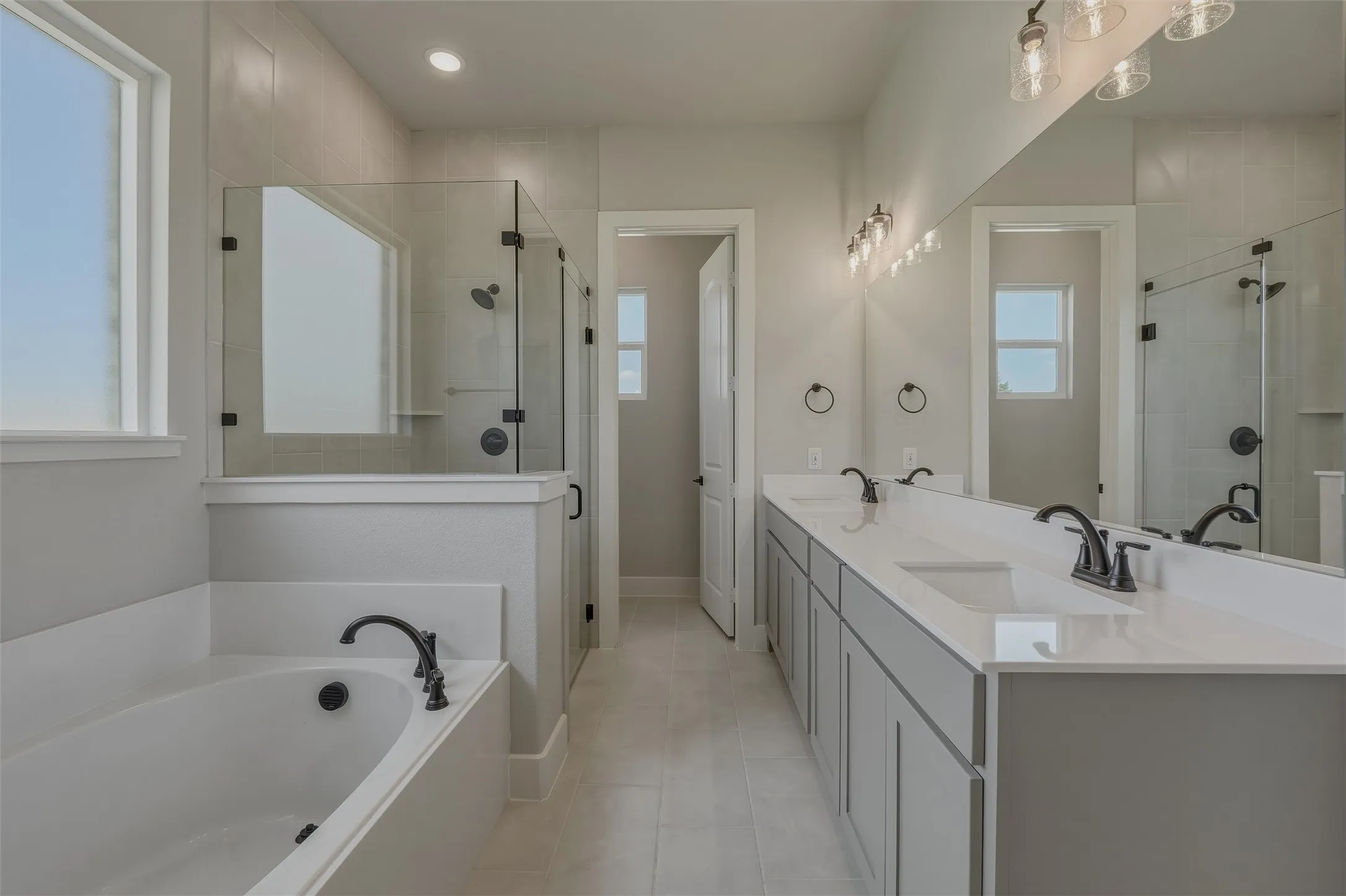 Spacious bathroom featuring a built-in soaking tub, a large walk-in shower with a glass enclosure, and a double vanity with an integrated countertop and undermount sinks