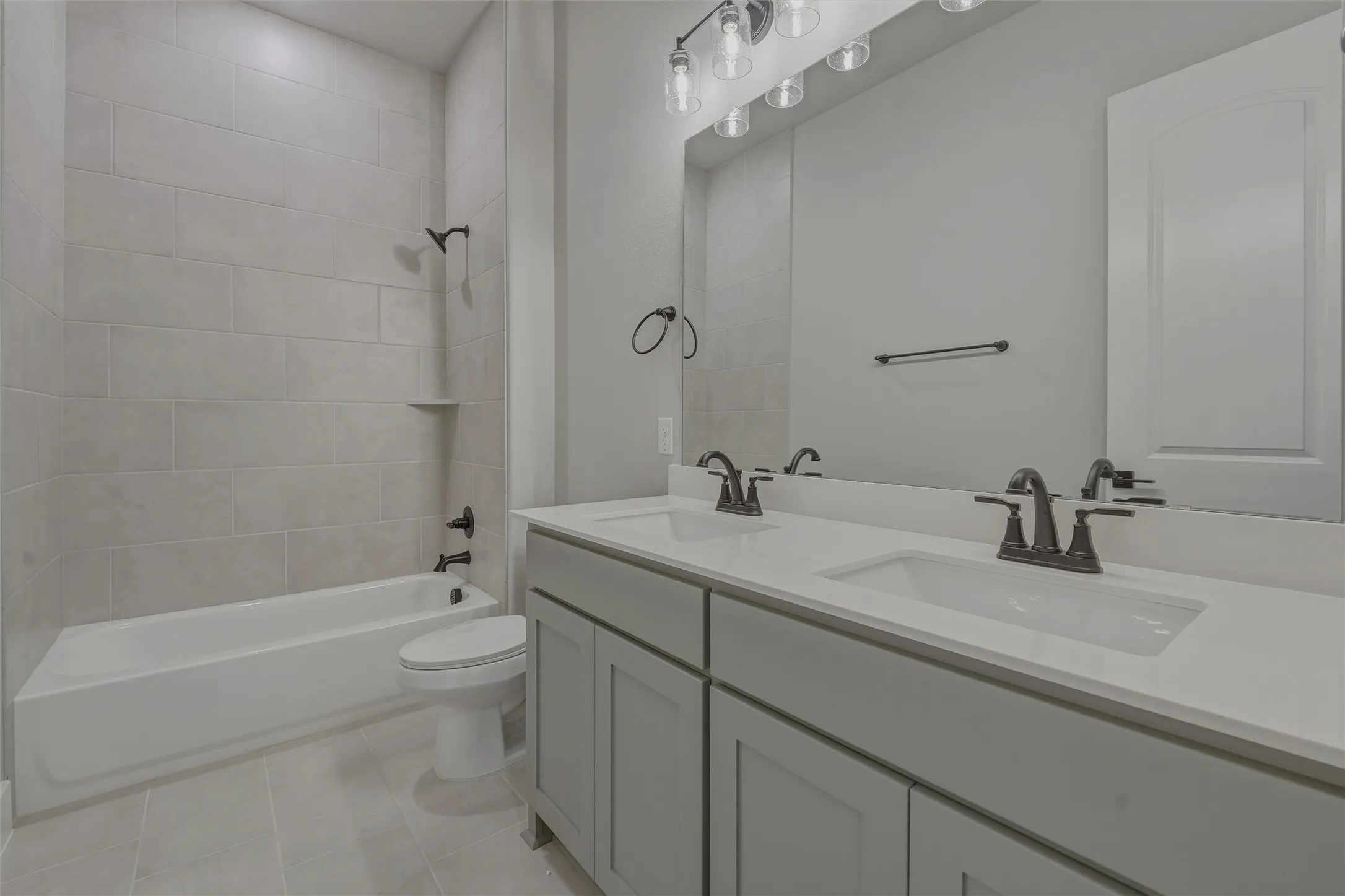 Dual vanity with white countertops and matte black fixtures, set against a full-width mirror