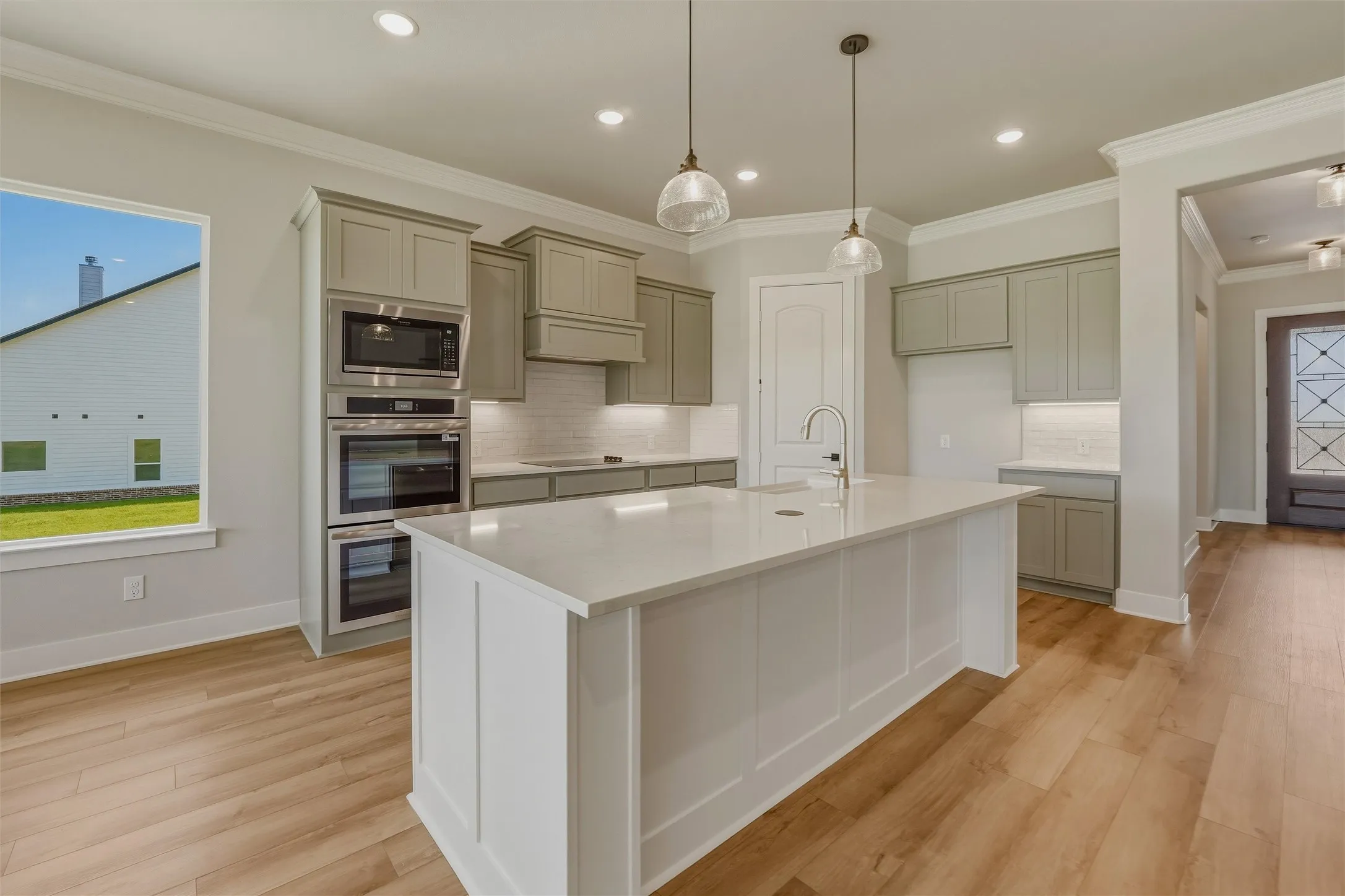 Kitchen featuring a central island with countertop seating space, stainless steel built-in appliances, under-cabinet lighting, and wood-finish flooring
