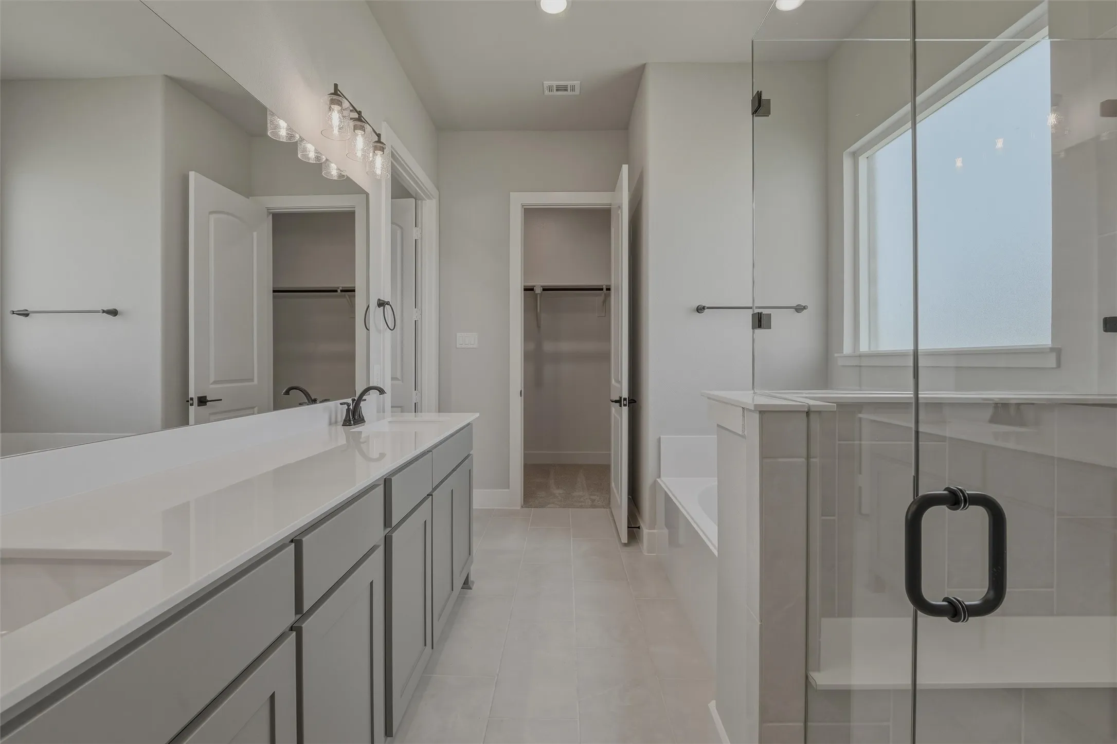 Spacious bathroom featuring a double vanity with light gray cabinetry and a white countertop