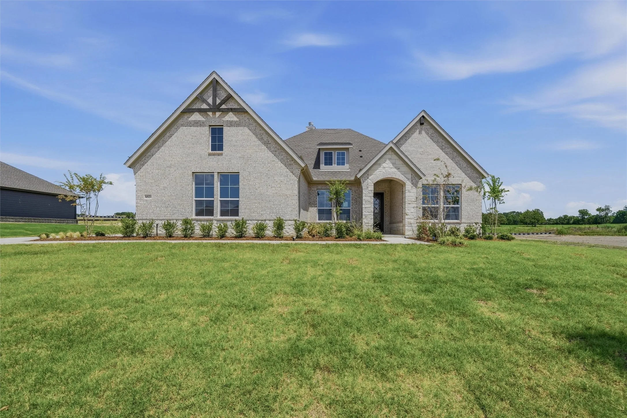 Light-colored brick exterior featuring stone accents, a gabled roofline, a prominent front entry, and multiple windows