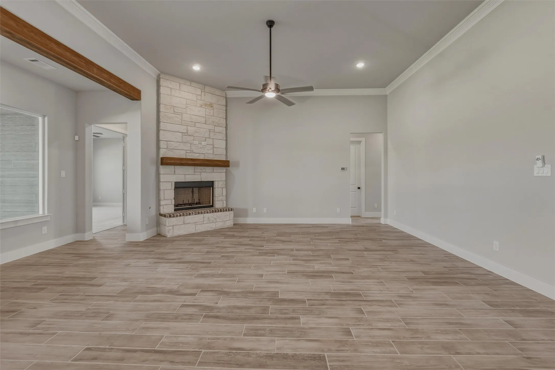 Spacious living area featuring plank-style flooring, a corner stone fireplace with a wood mantle, and recessed lighting