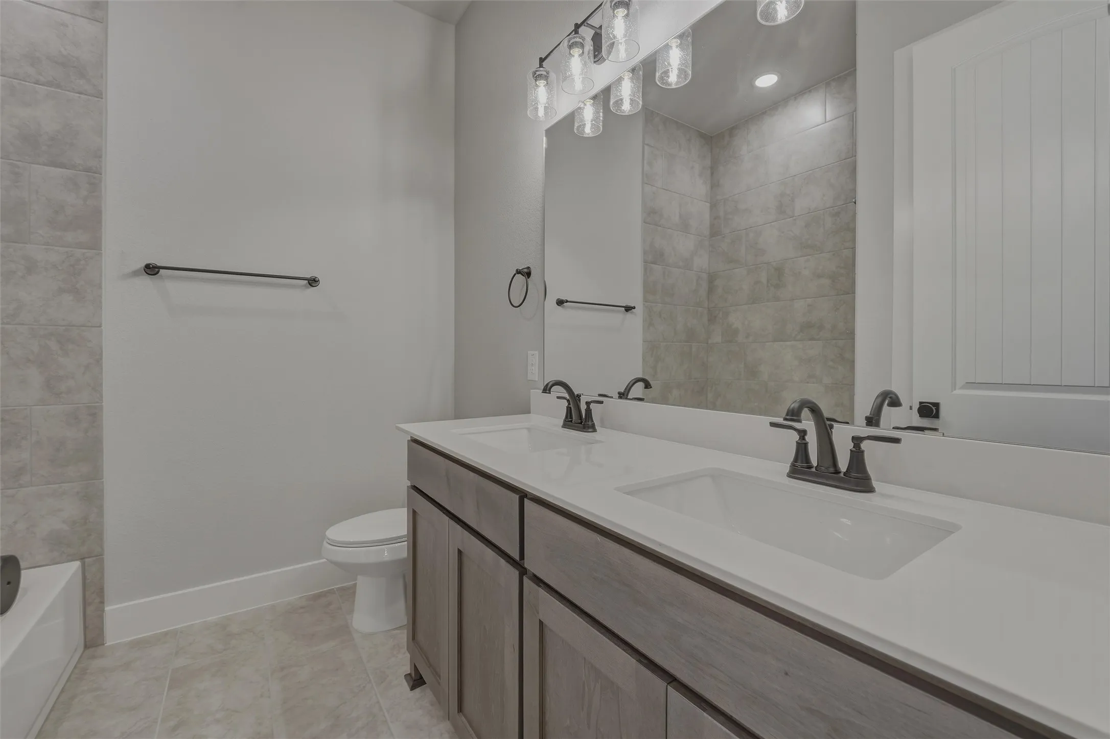 Bathroom featuring a dual vanity with white countertops, undermount sinks, and dark bronze fixtures