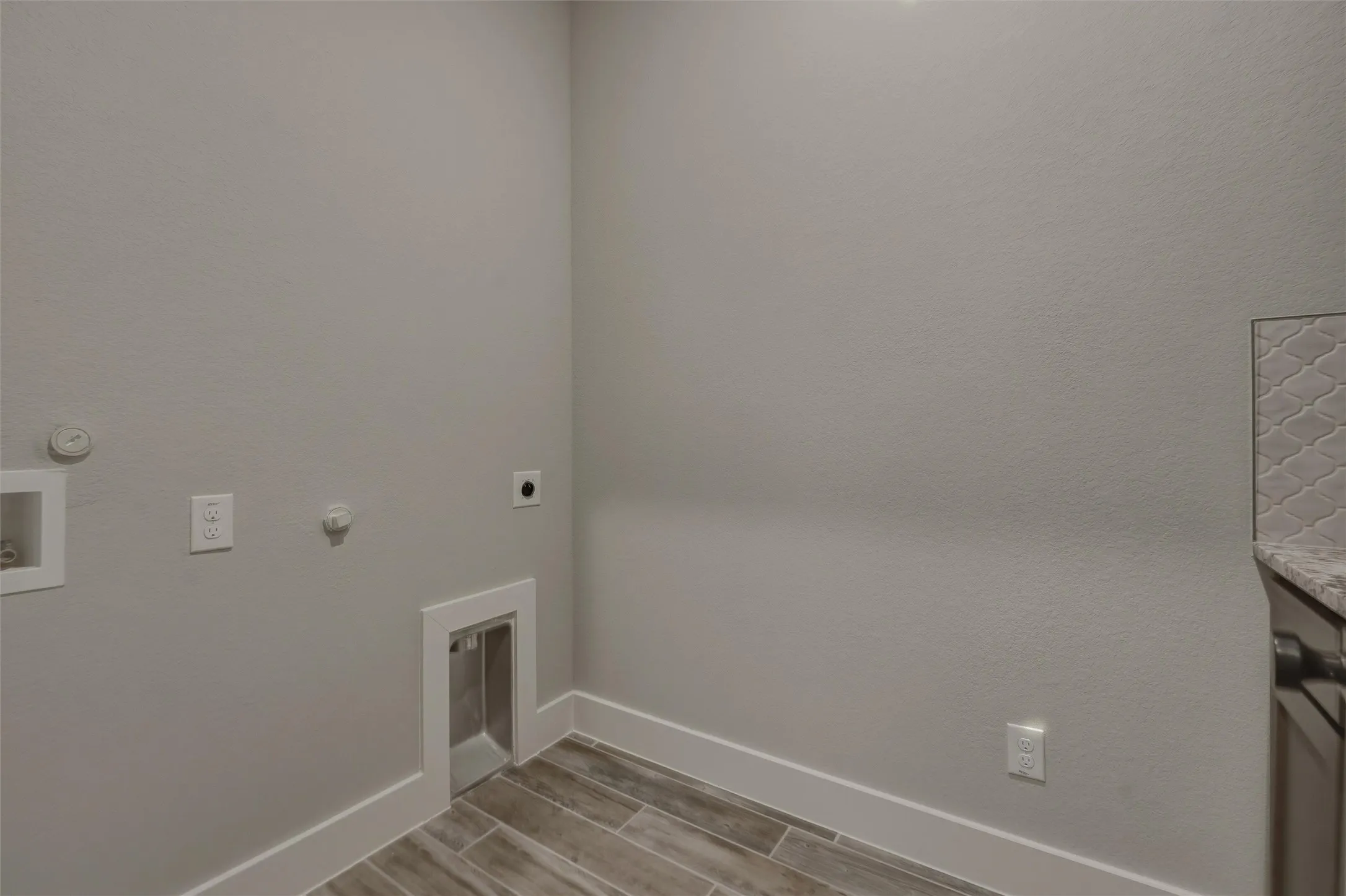 Laundry area with wood-finish tile flooring, light gray wall paint, and white trim