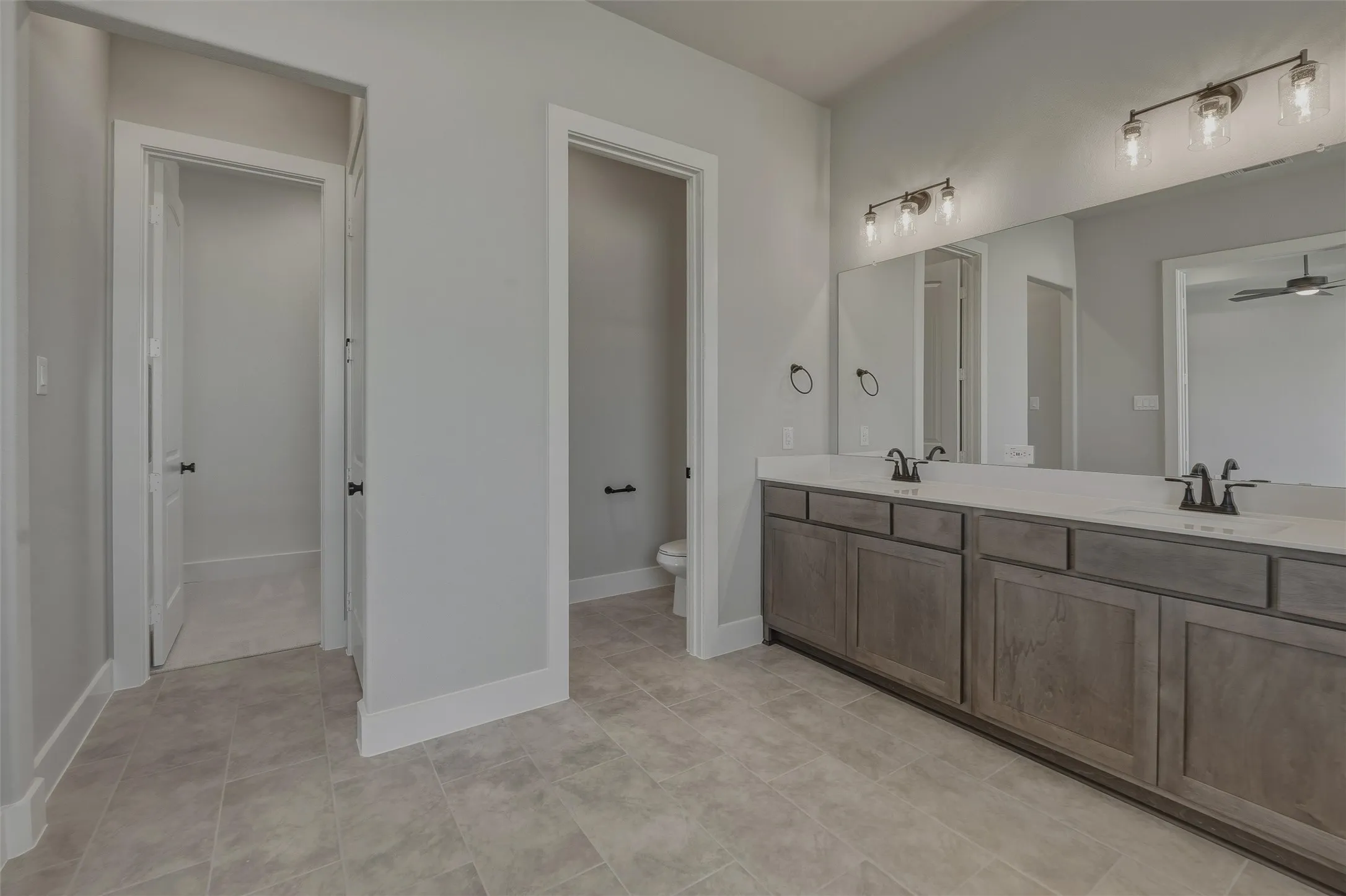 Dual vanity with light wood-finish cabinetry, white countertops, and undermount sinks