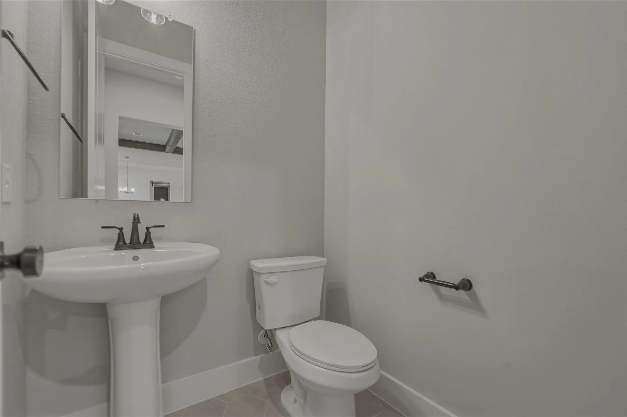 Pedestal sink featuring a matte black faucet and coordinating mirror