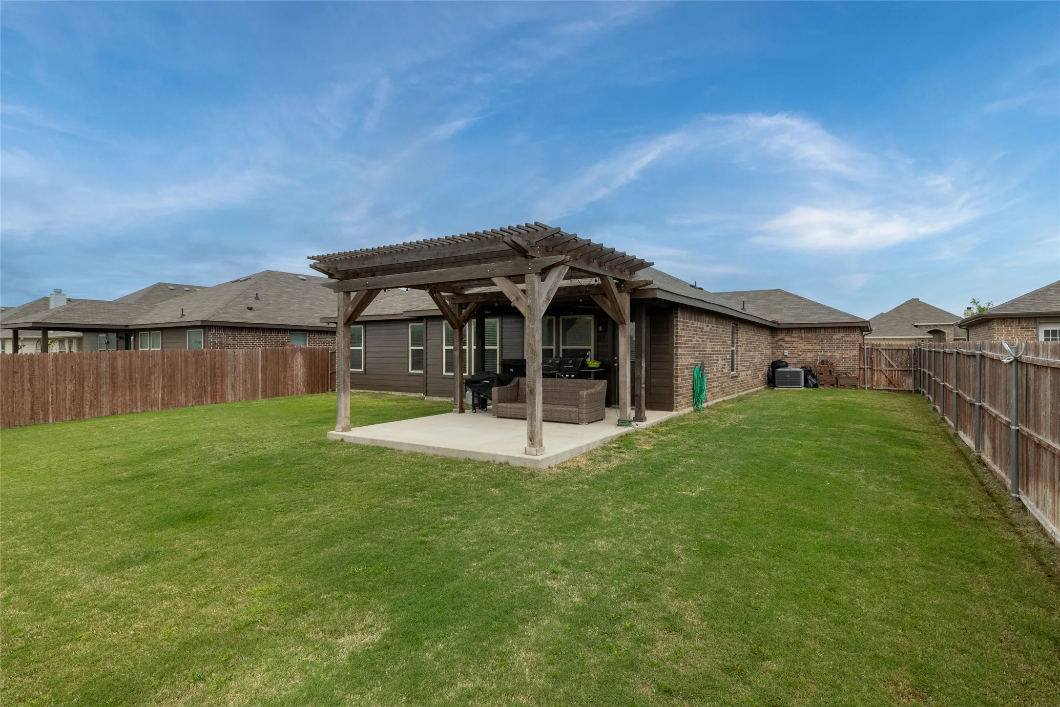 Rear view of house featuring a pergola, a patio area, brick siding, a fenced backyard, and outdoor lounge area