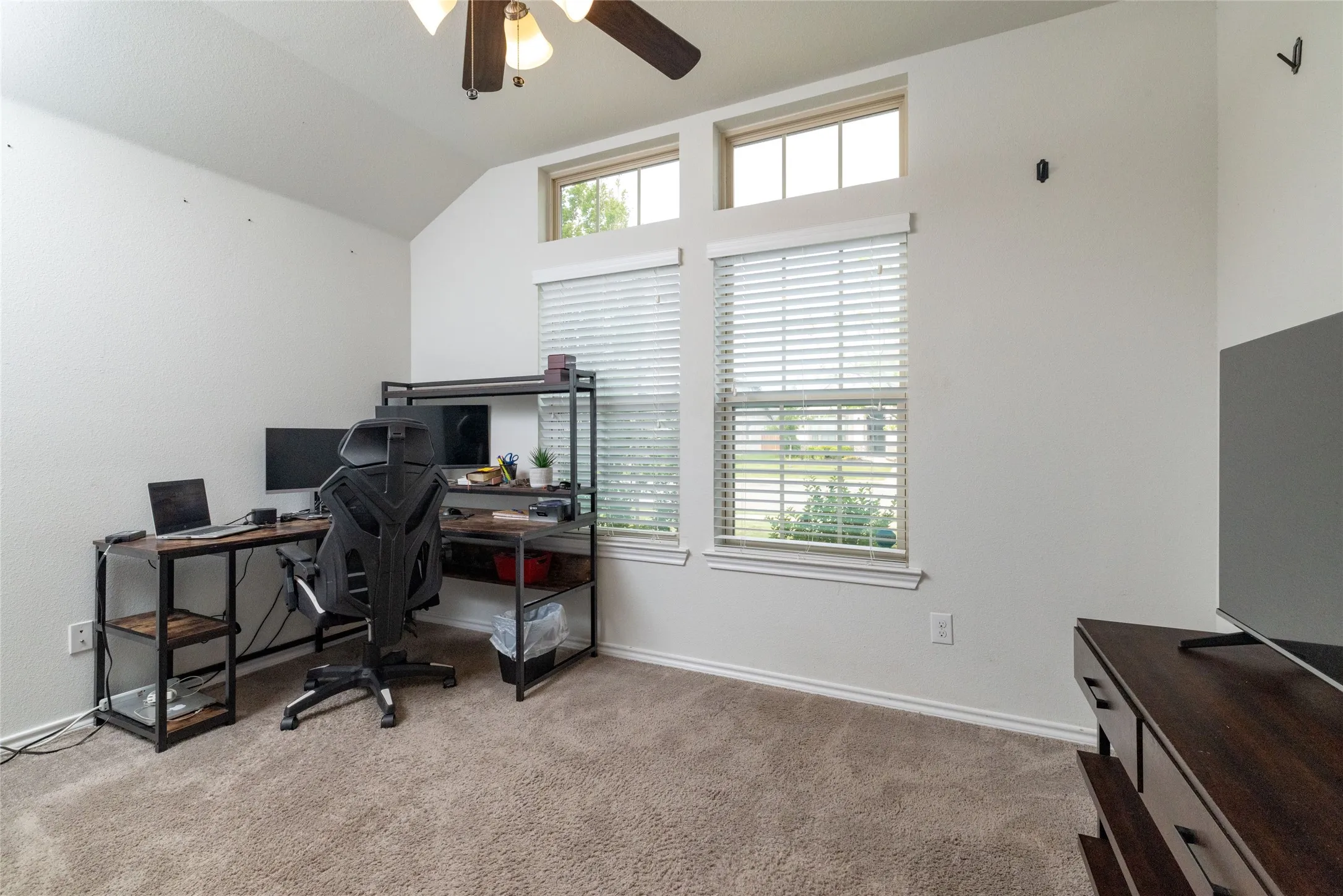 Office space with ceiling fan, light carpet, and vaulted ceiling