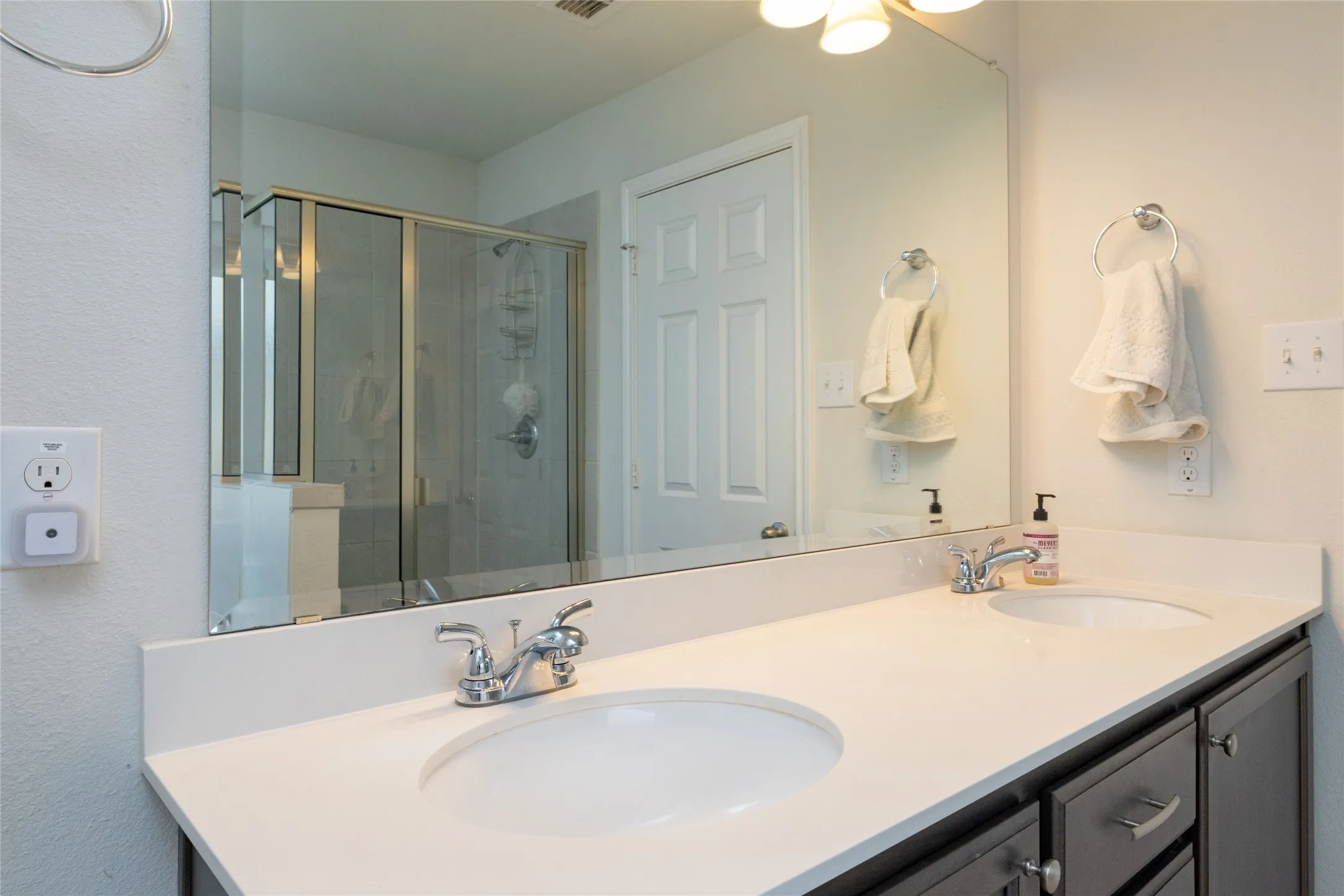 Bathroom featuring double vanity and a shower stall