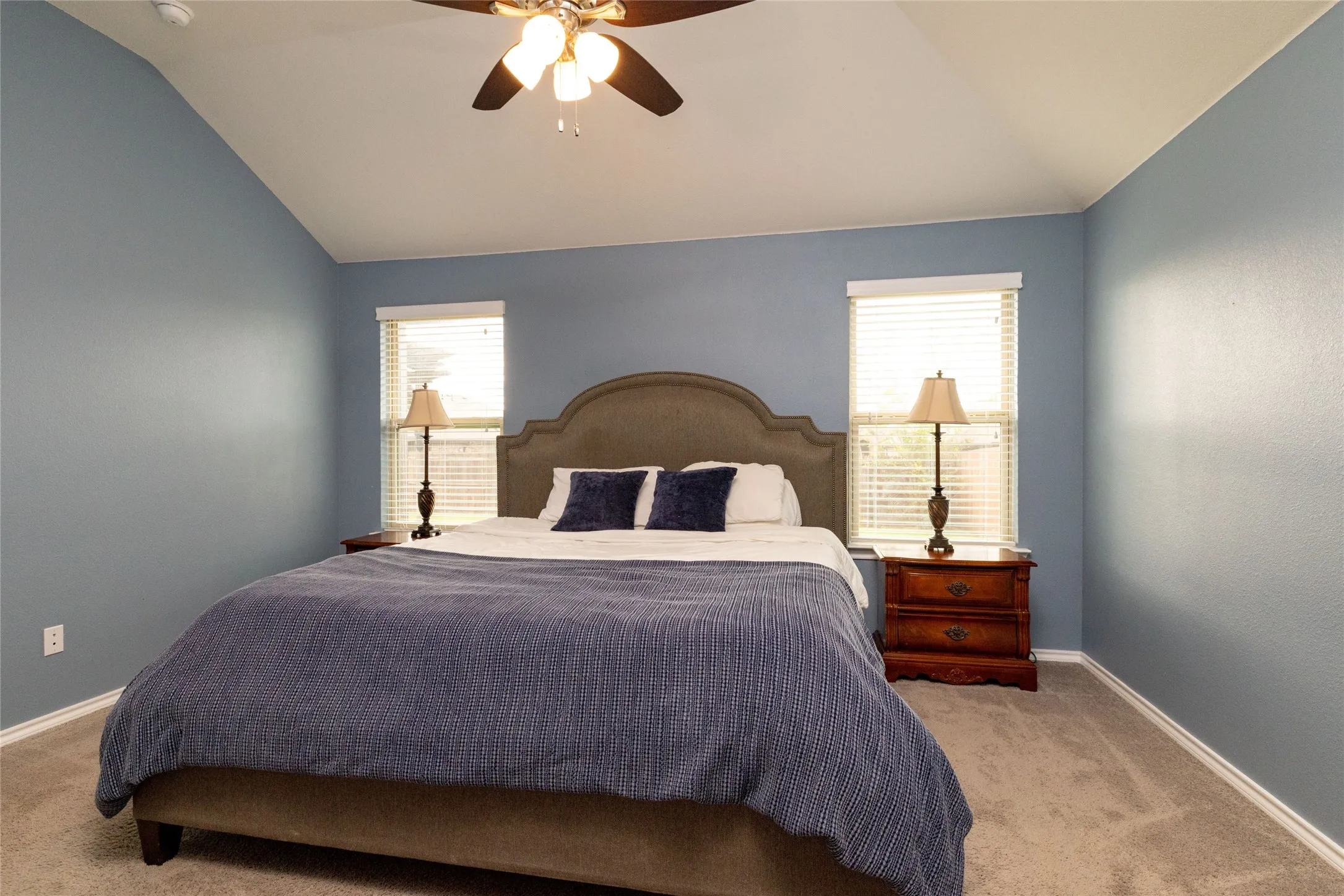 Bedroom featuring light carpet, multiple windows, a ceiling fan, and lofted ceiling