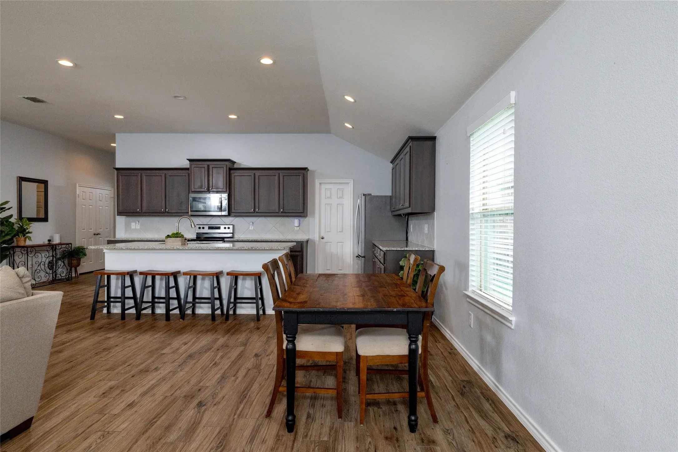 Dining room featuring dark wood-style flooring, lofted ceiling, and recessed lighting