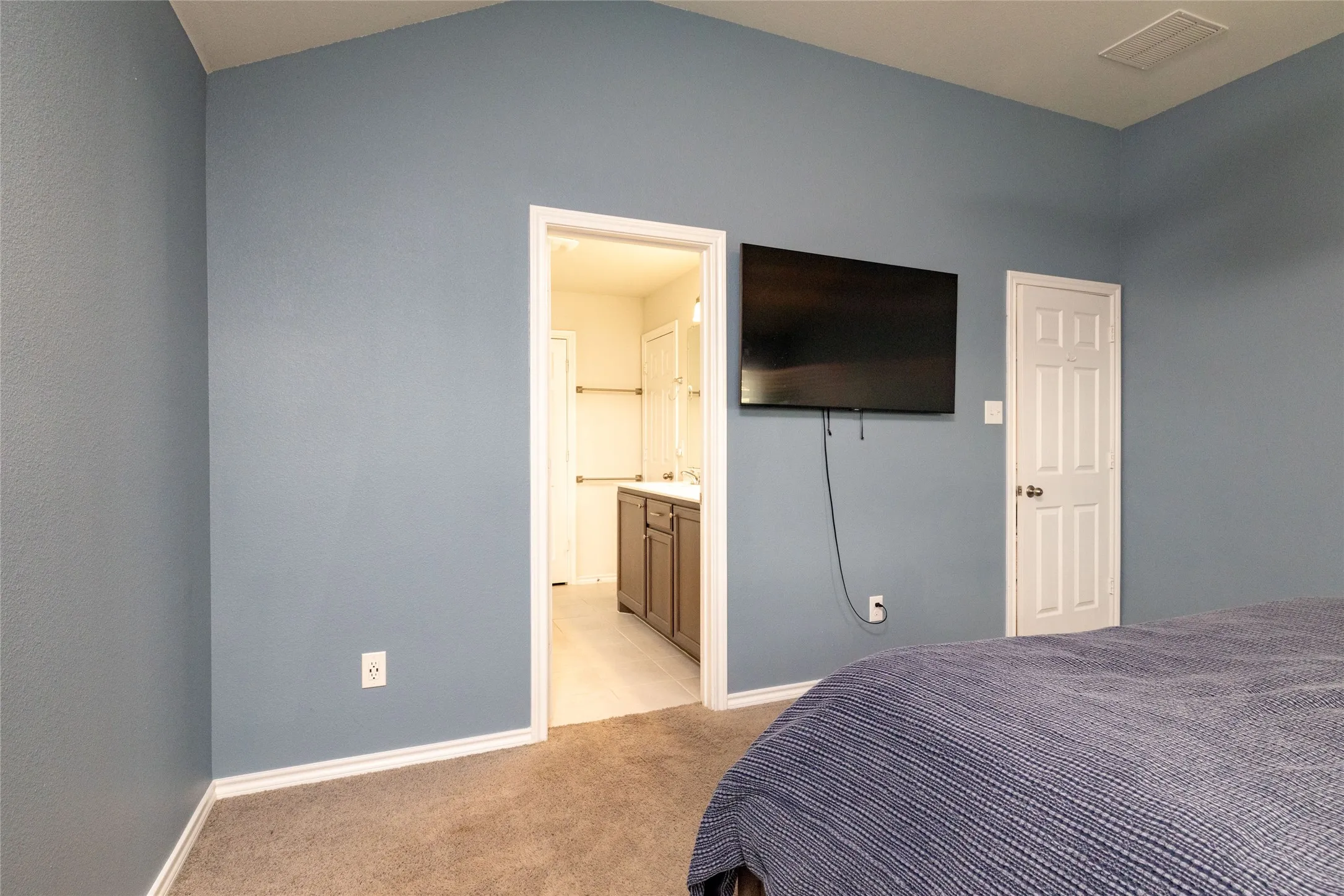 Bedroom featuring light carpet and connected bathroom