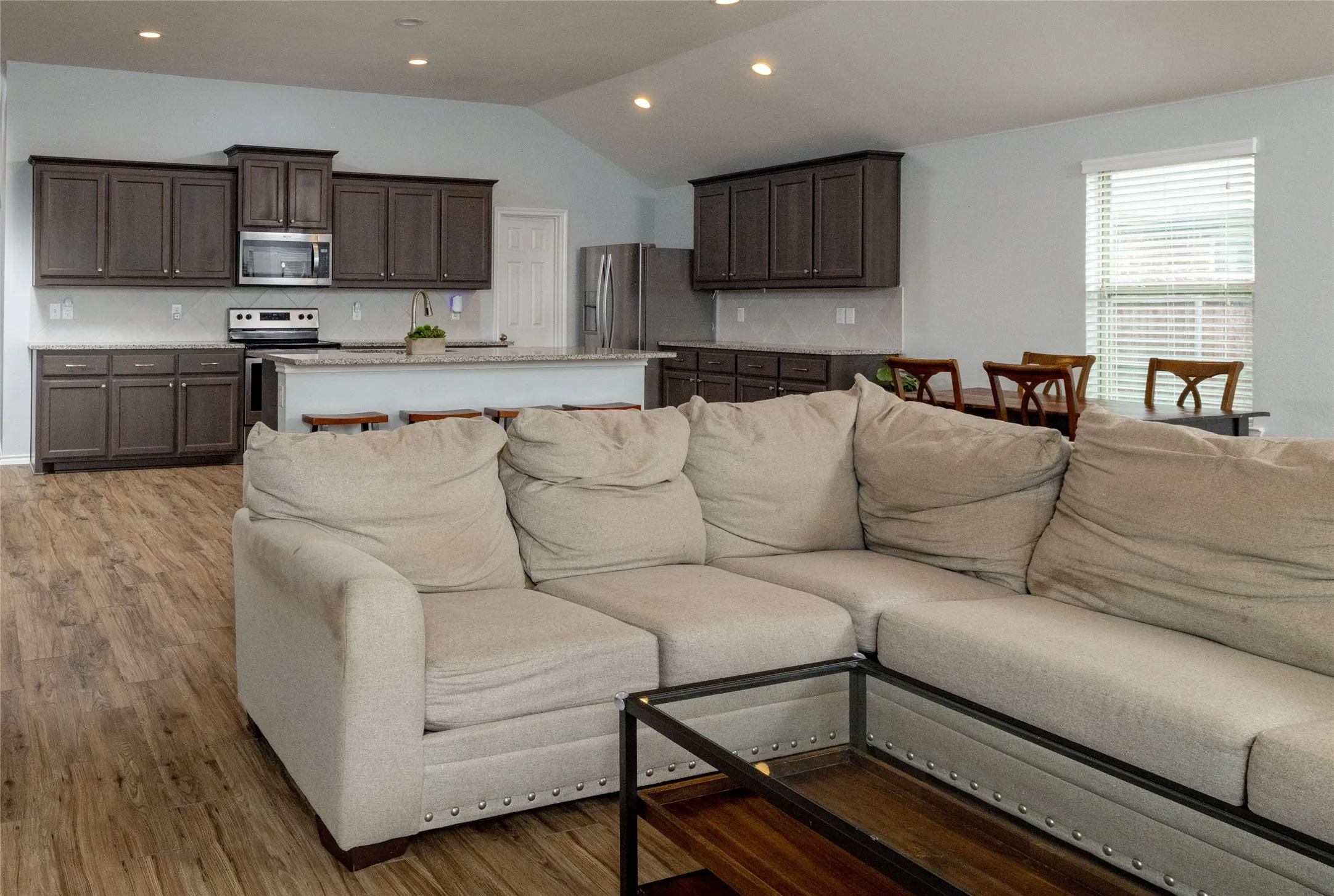 Living area with lofted ceiling, light wood-style flooring, and recessed lighting