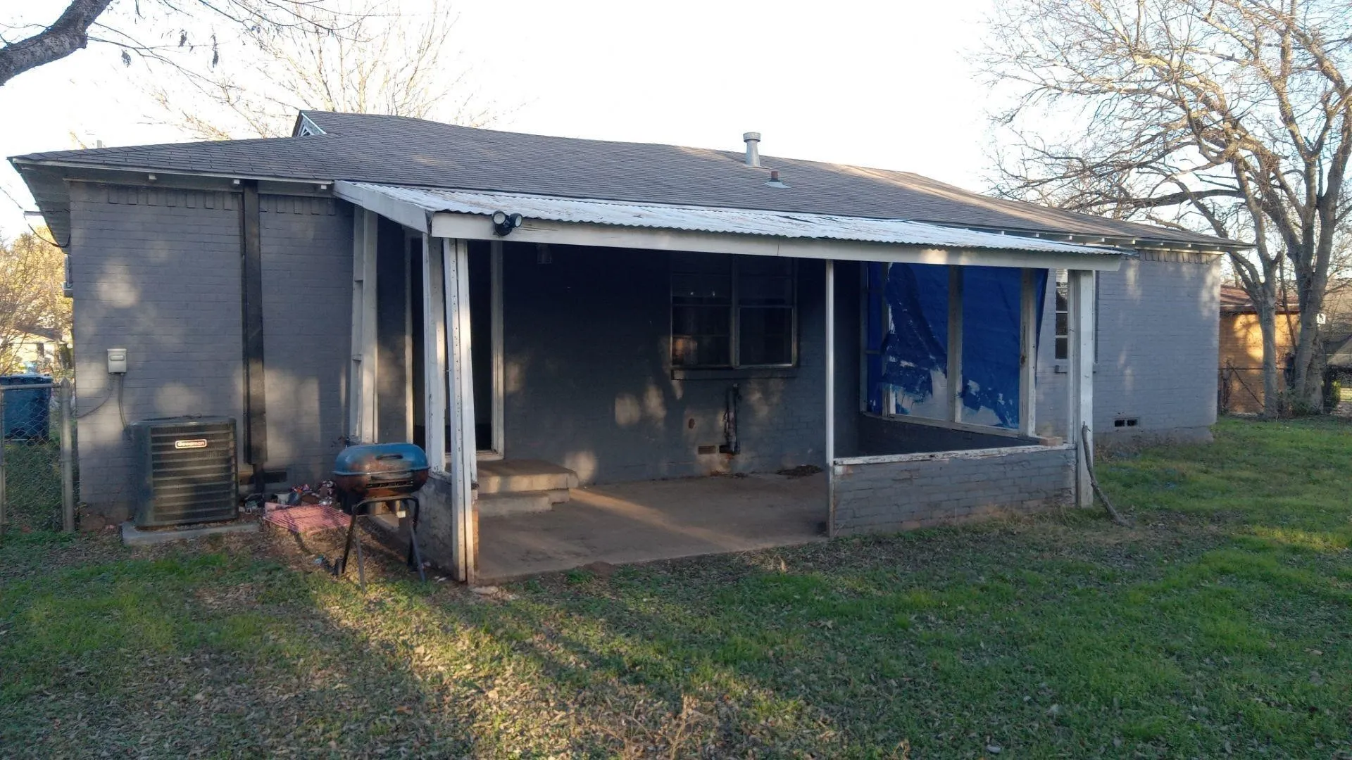 Back of property featuring a lawn, brick siding, and a metal roof
