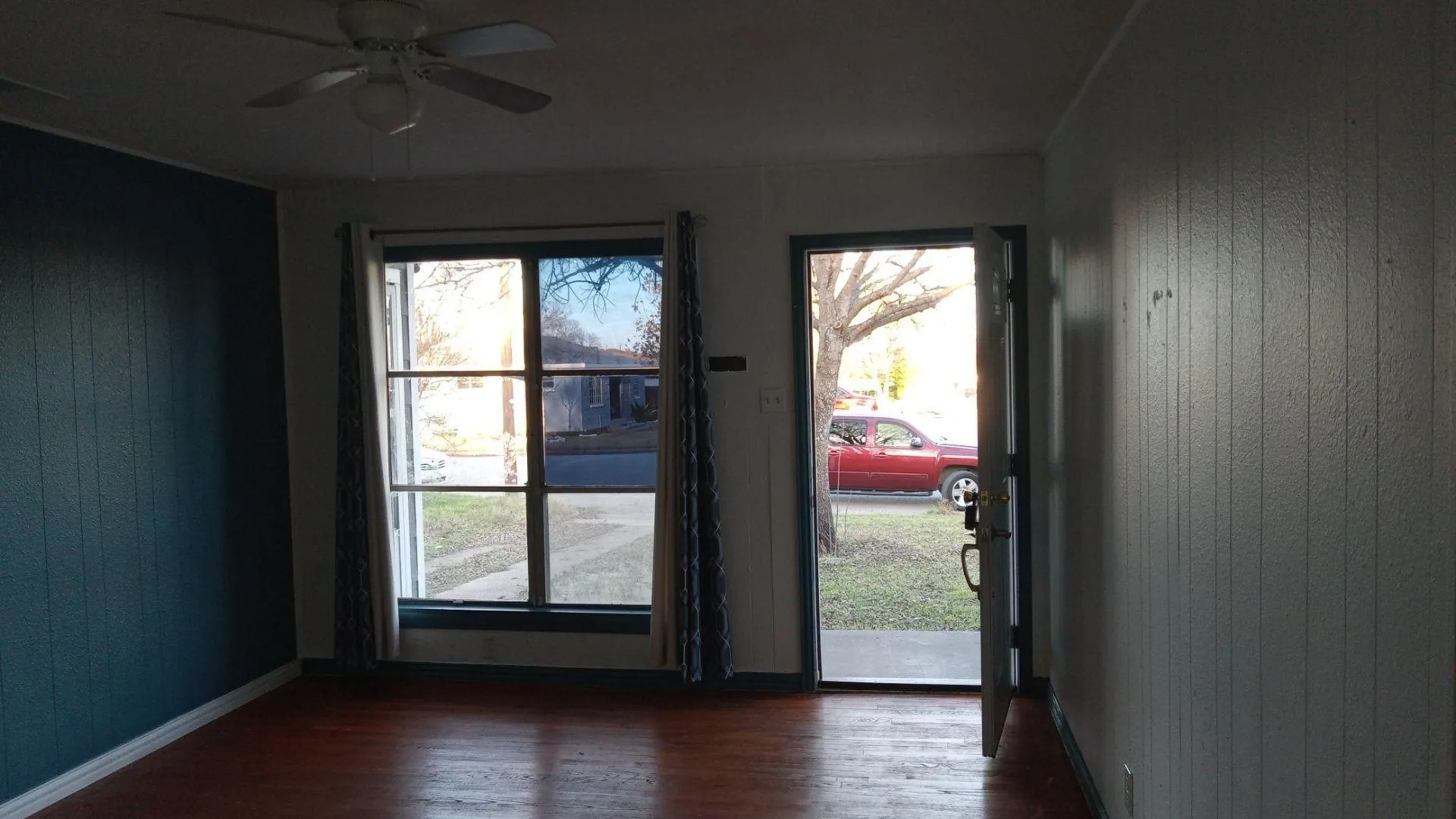 Doorway to outside featuring wooden walls, wood finished floors, plenty of natural light, and a ceiling fan