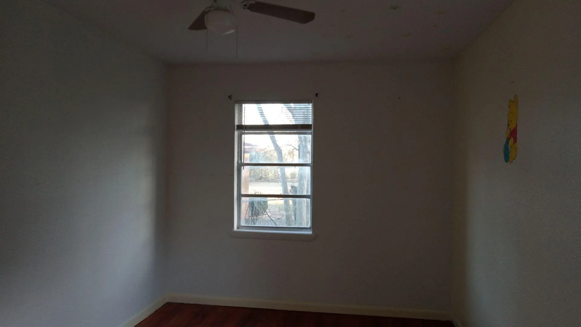 Empty room with dark wood finished floors and ceiling fan