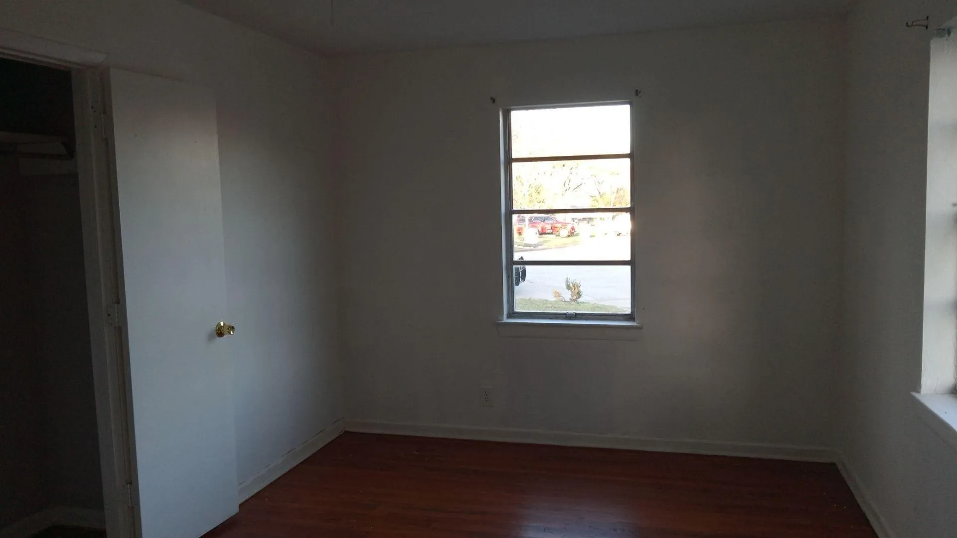 Unfurnished room with dark wood-type flooring and baseboards