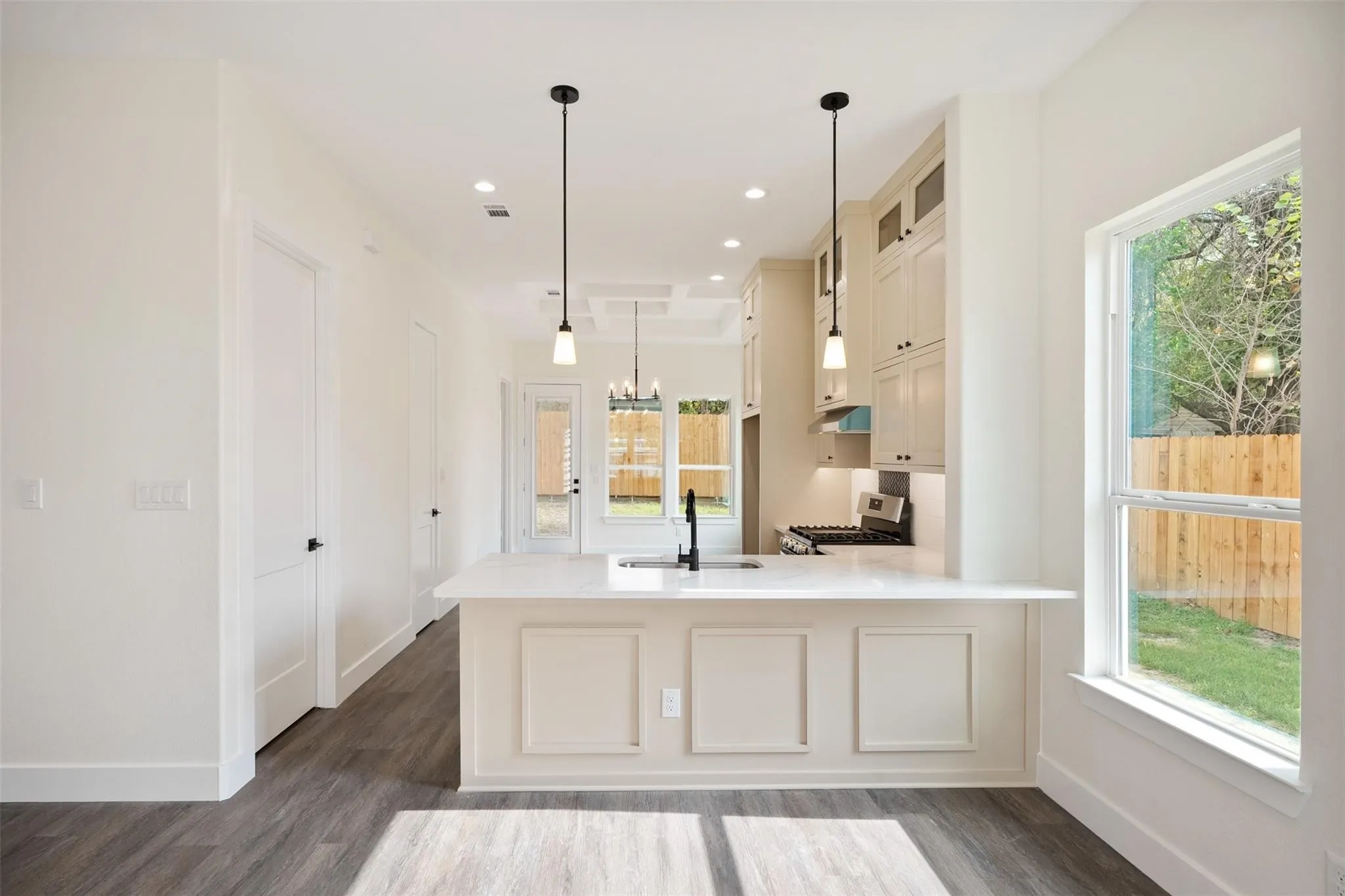 Kitchen featuring dark wood-type flooring, stainless steel range with gas cooktop, a peninsula, a chandelier, and glass fronted cabinets