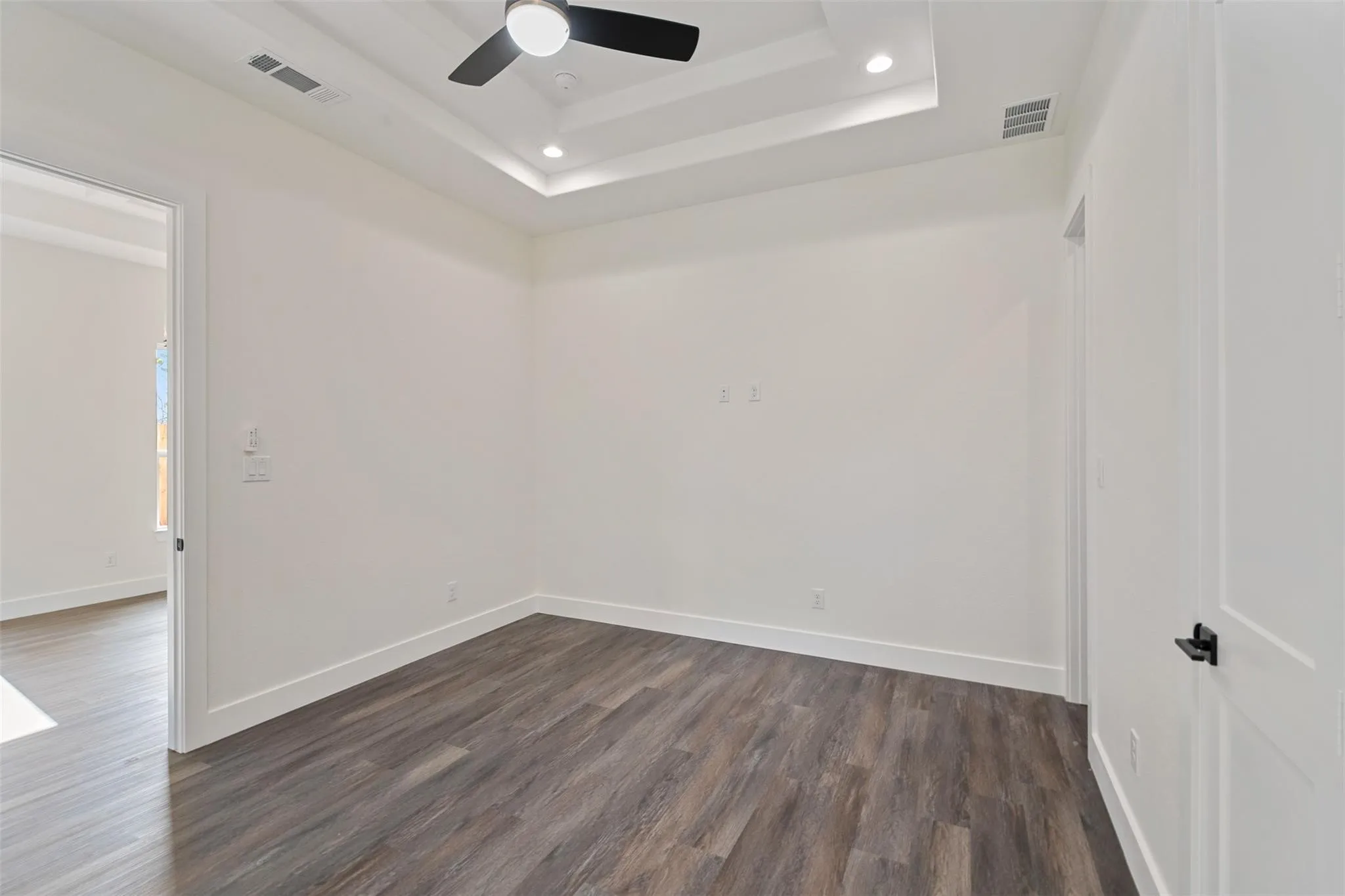 Empty room with a ceiling fan, dark wood-style floors, recessed lighting, and a raised ceiling