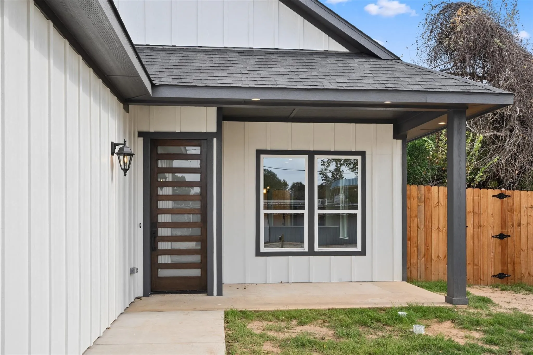 View of exterior entry featuring roof with shingles and a gate
