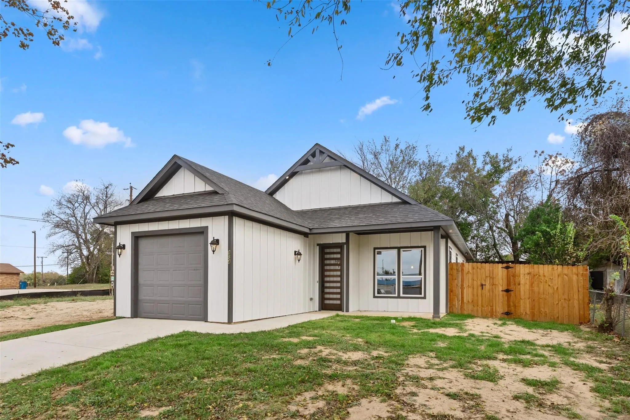 View of front of home with a shingled roof, an attached garage, a gate, and concrete driveway