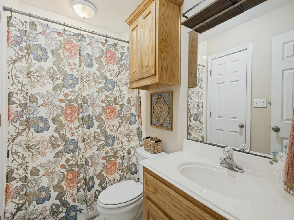 Vanity with integrated sink, wood-finish cabinetry, and overhead wood-finish storage