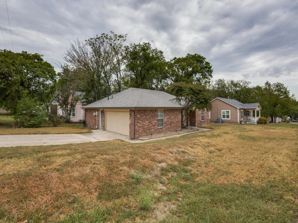 Brick exterior with an attached garage and concrete driveway on a corner lot.