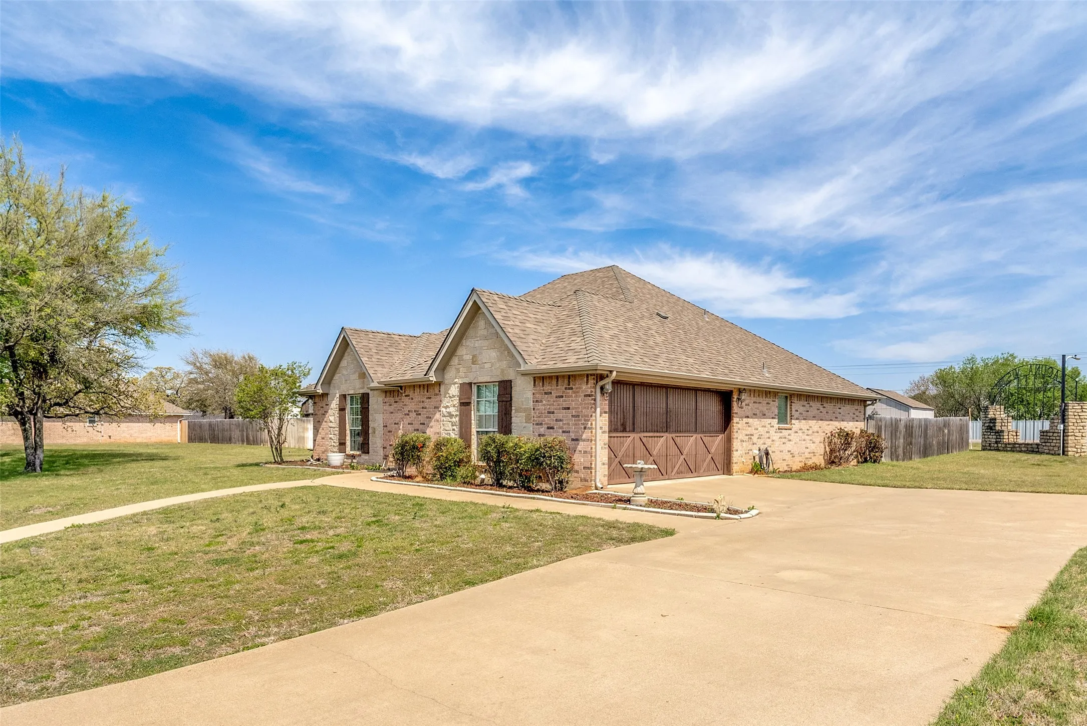 View of front of property with brick siding, a shingled roof, concrete driveway, and a garage