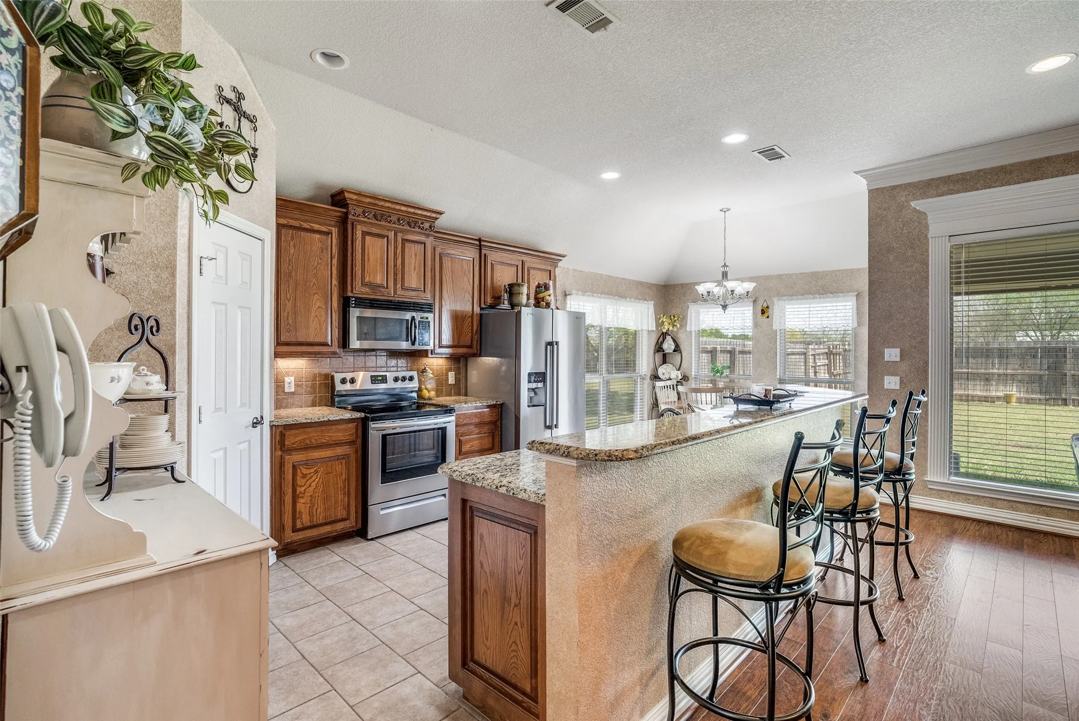 Kitchen featuring stainless steel appliances, a chandelier, wood finish cabinets, a kitchen bar, and a kitchen island