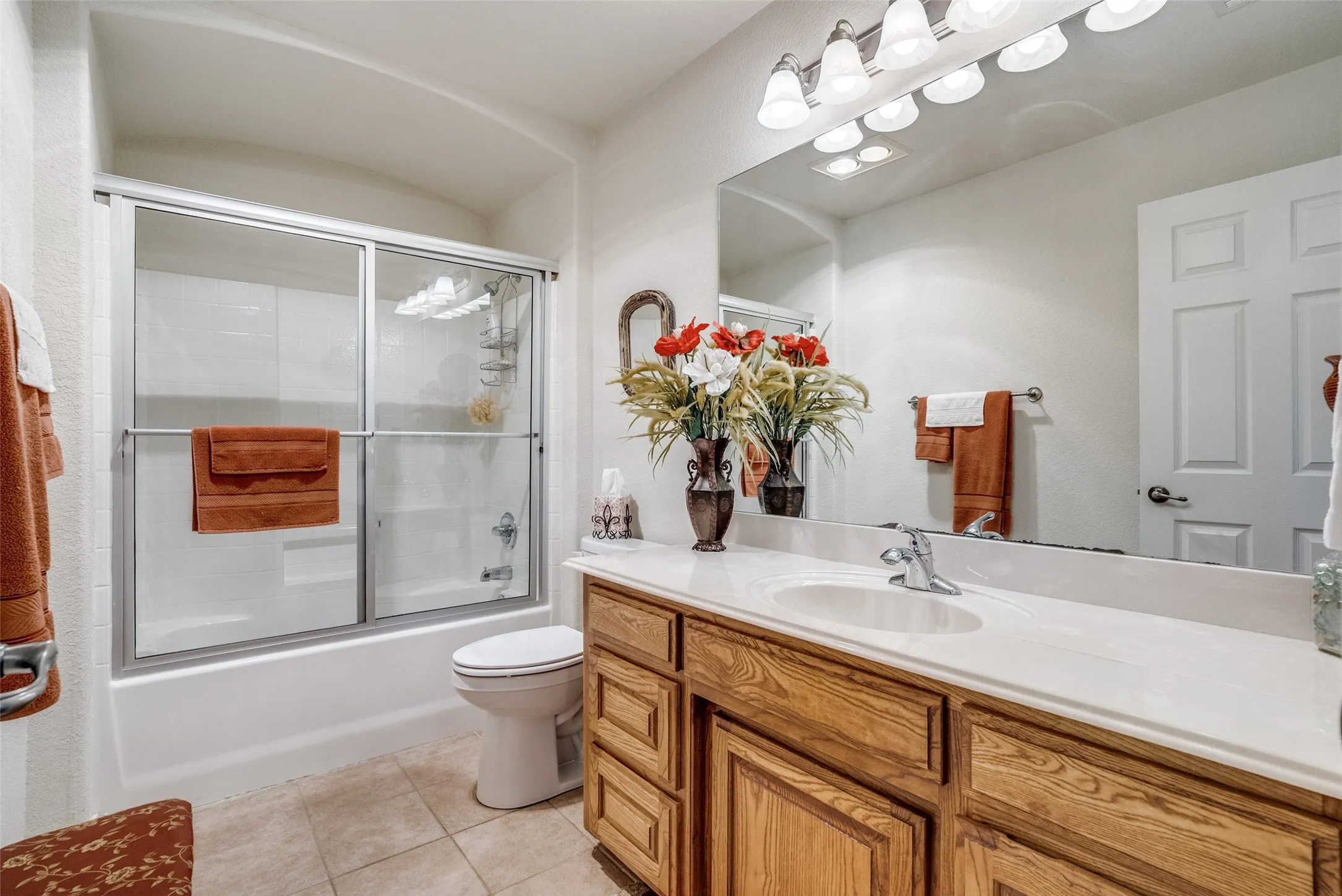 Full bathroom with vanity, light tile patterned floors, and enclosed tub / shower combo