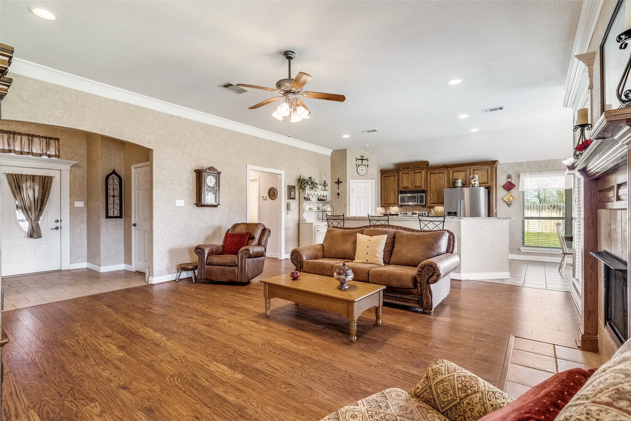 Living room featuring light wood finished floors, recessed lighting, ornamental molding, a ceiling fan, and arched walkways